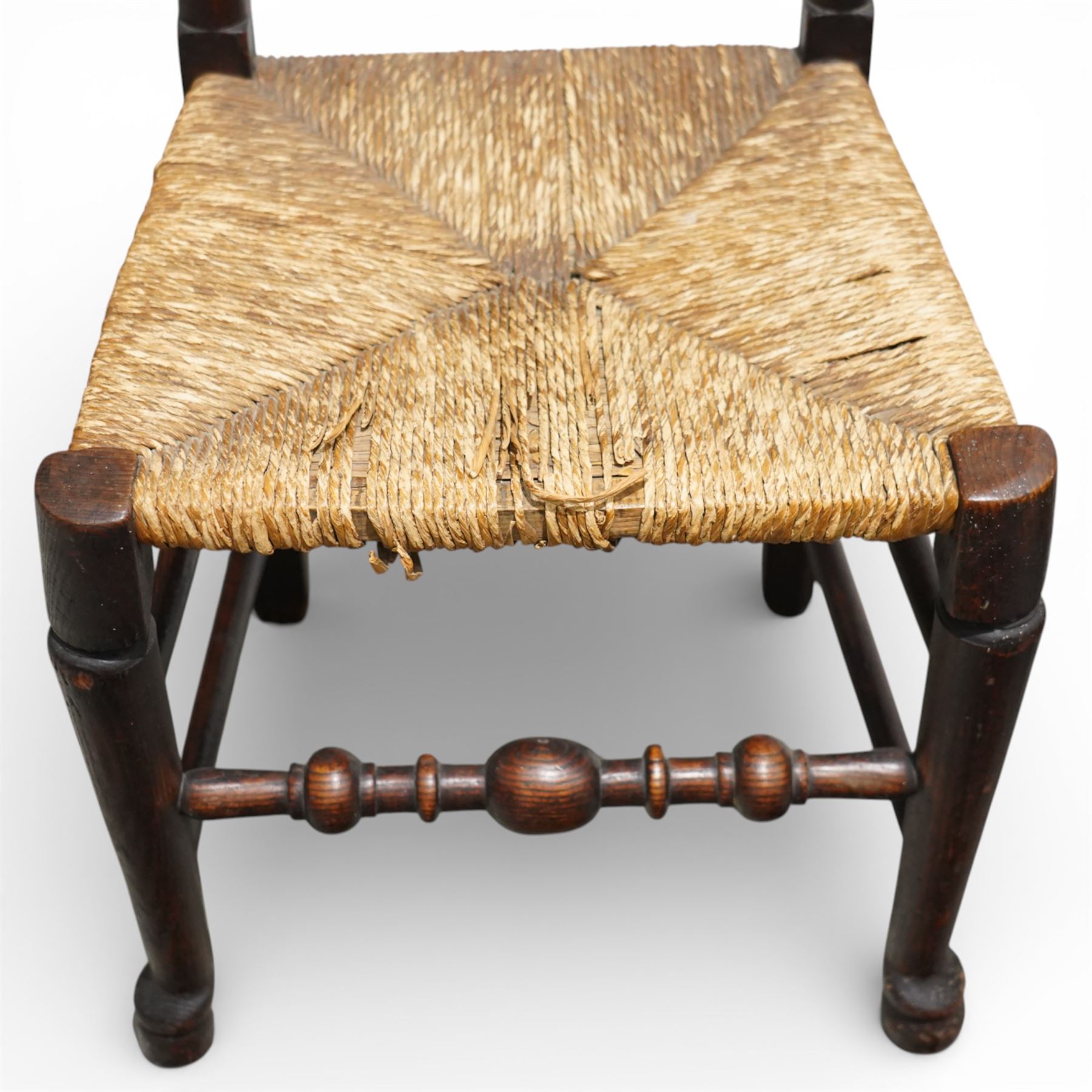 Set of five 19th century elm spindle back chairs, with shaped crest rails above double rows of turned spindles, rush seats, turned legs joined by stretchers supported on turned pad feet