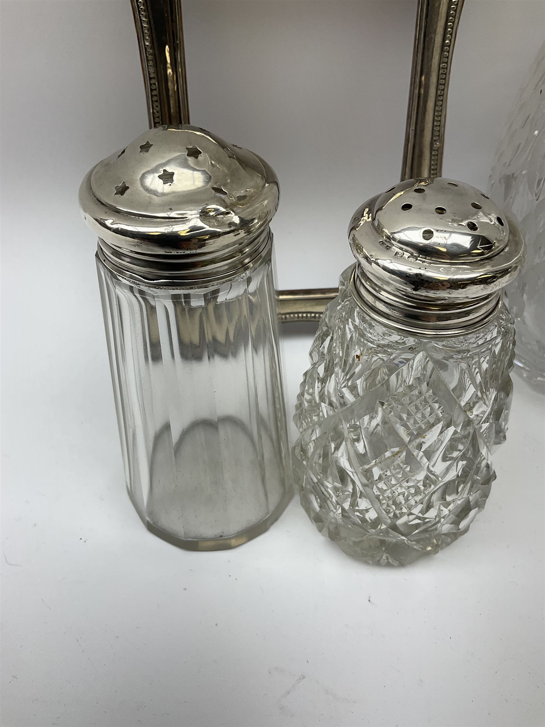 Clear glass decanter of slender oviform with silver collar stamped MN & WB 925, Mappin & Webb, together with an early 20th century silver photo frame hallmarked G & C Ltd of Birmingham, two clear glass shakers with pierced silver tops and silver collared glass storm lampshade with etched decoration, tallest H37.5cm