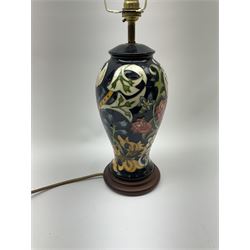 A Moorcroft table lamp, of baluster form, decorated in the Golden Lily pattern upon a dark blue ground, with accompanying cream shade of lobed form, with piped detail, overall H59cm.