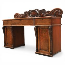 Mid Victorian mahogany pedestal sideboard, the rectangular top with raised back centred by a carved shell within scrolling acanthus and foliate cresting, over a central shaped frieze drawer flanked by two short drawers, above a kneehole recess, flanked by panelled cupboard doors with carved corbel supports, enclosing shelved interiors