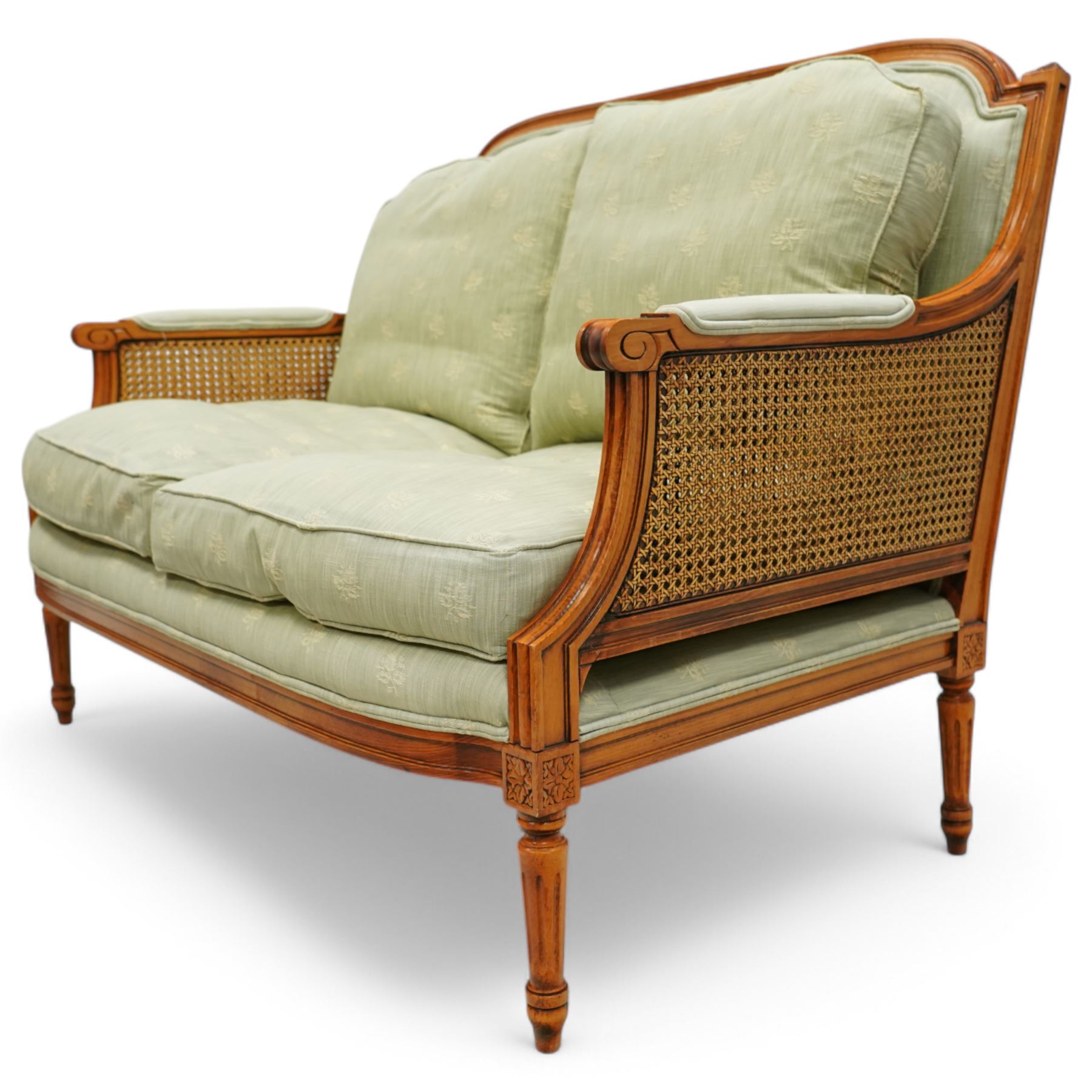 French Empire design varnished wood three piece lounge suite comprising of two cane armchairs and matching sofa, carved top rails with foliate terminals, cane side panels and padded scroll arms, upholstered in a green brocade with matching piping, on fluted legs