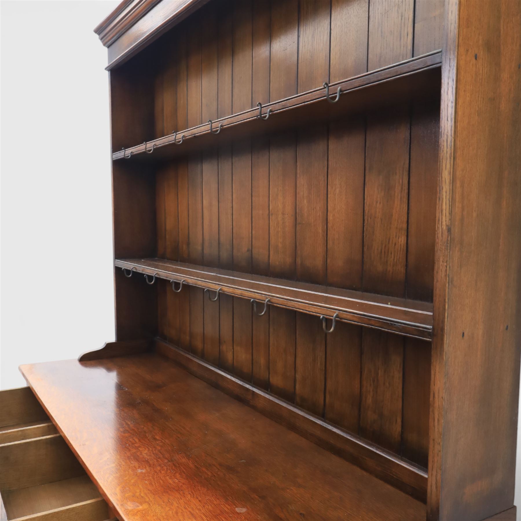 Georgian style oak dresser, the moulded cornice above two open plate racks, upon base with rectangular top above an arrangement of three frieze drawers fitted with brass swan neck handles, and three panelled cupboard doors, upon bracket feet