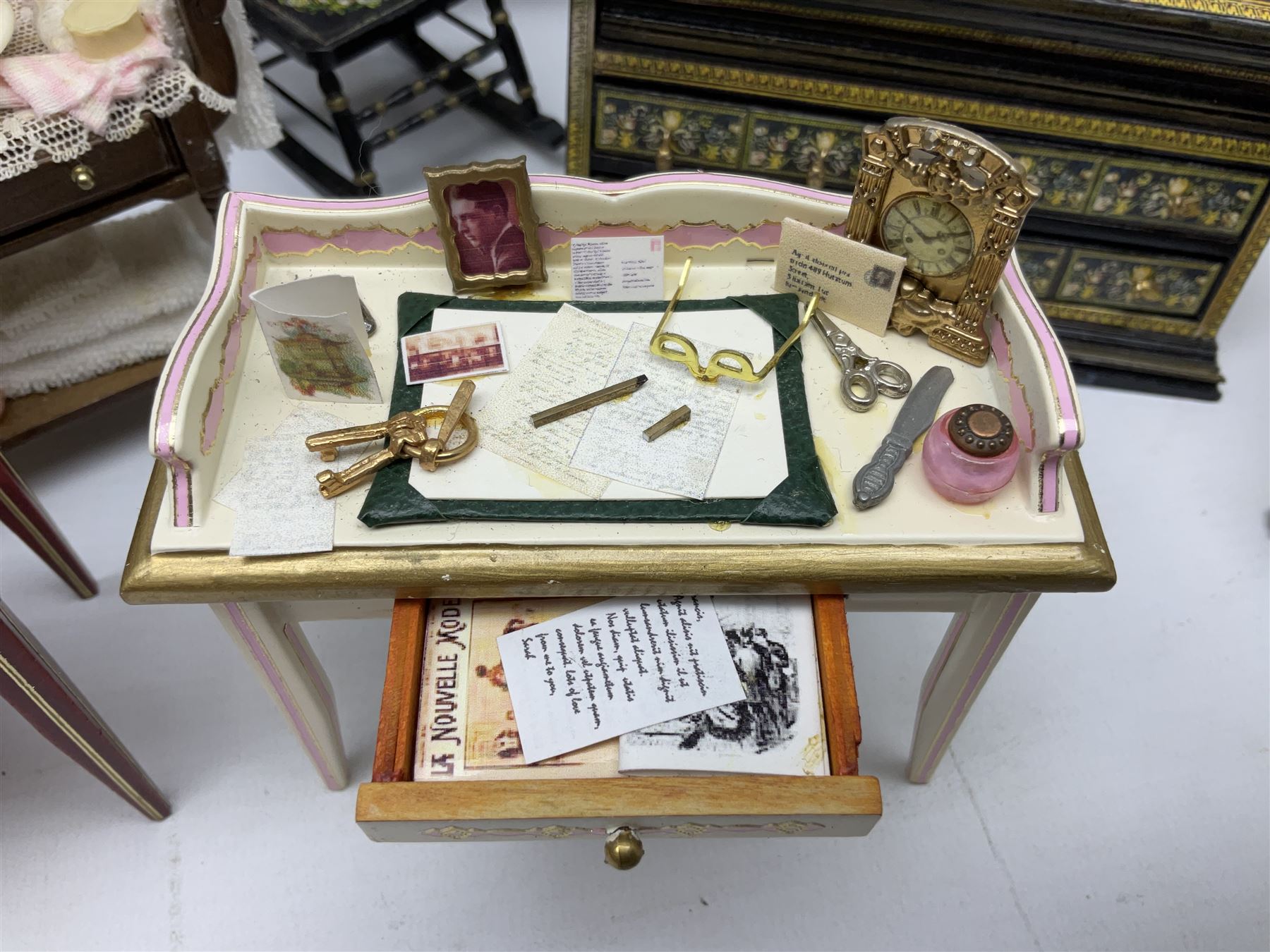 Collection of miniature dolls house furniture, to include five drawer chest painted with blossom, cream and gilt double door mirrored wardrobe, four piece lacquered style desk set, three piece suite, writing desk, wash stand, Knoll style sofa etc (14)