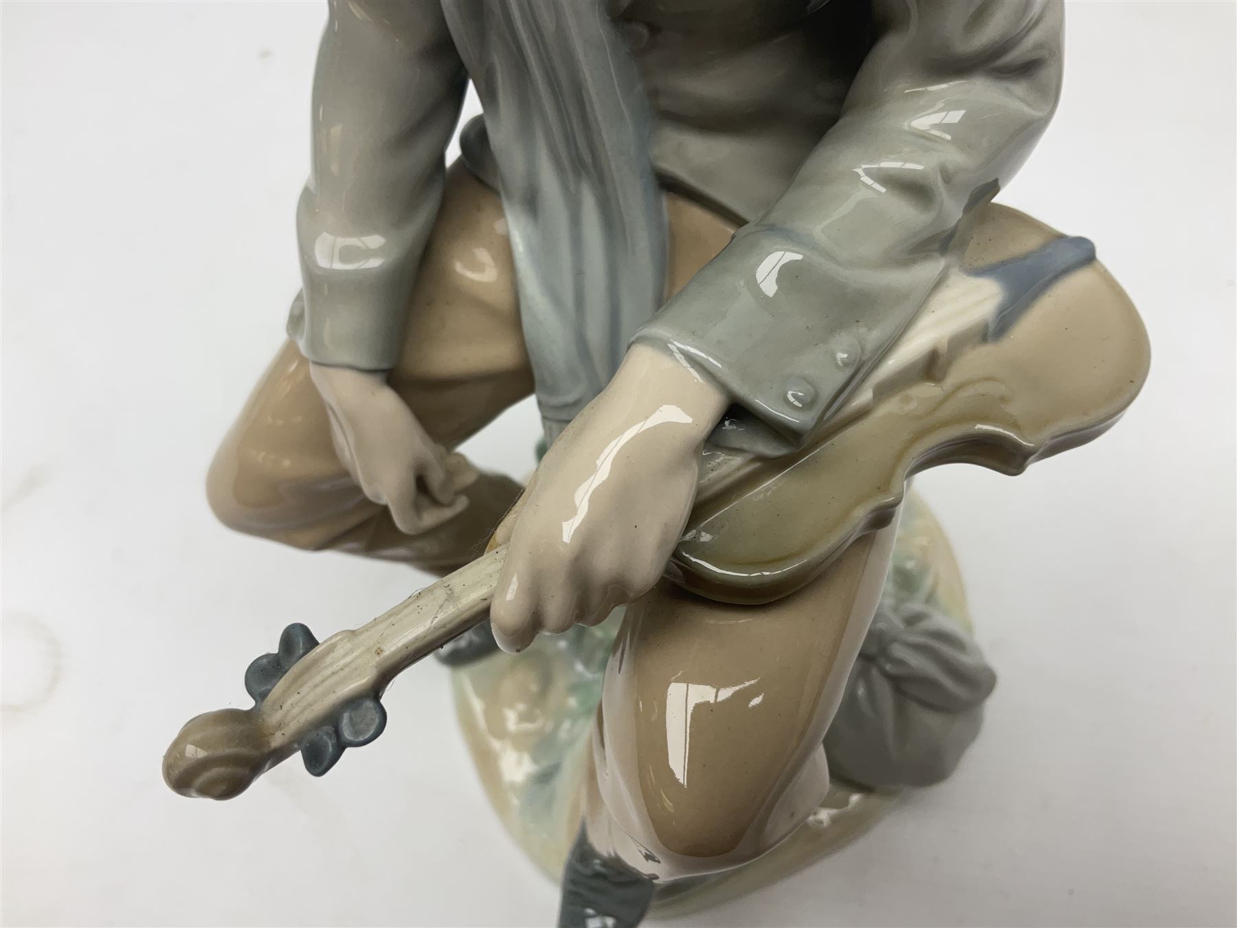 Lladro figure, Violinist, modelled as a man seated upon a  mile stone holding a violin, sculpted by Salvador Furió, no 4887,  year issued 1984, year retired 1981, H35cm