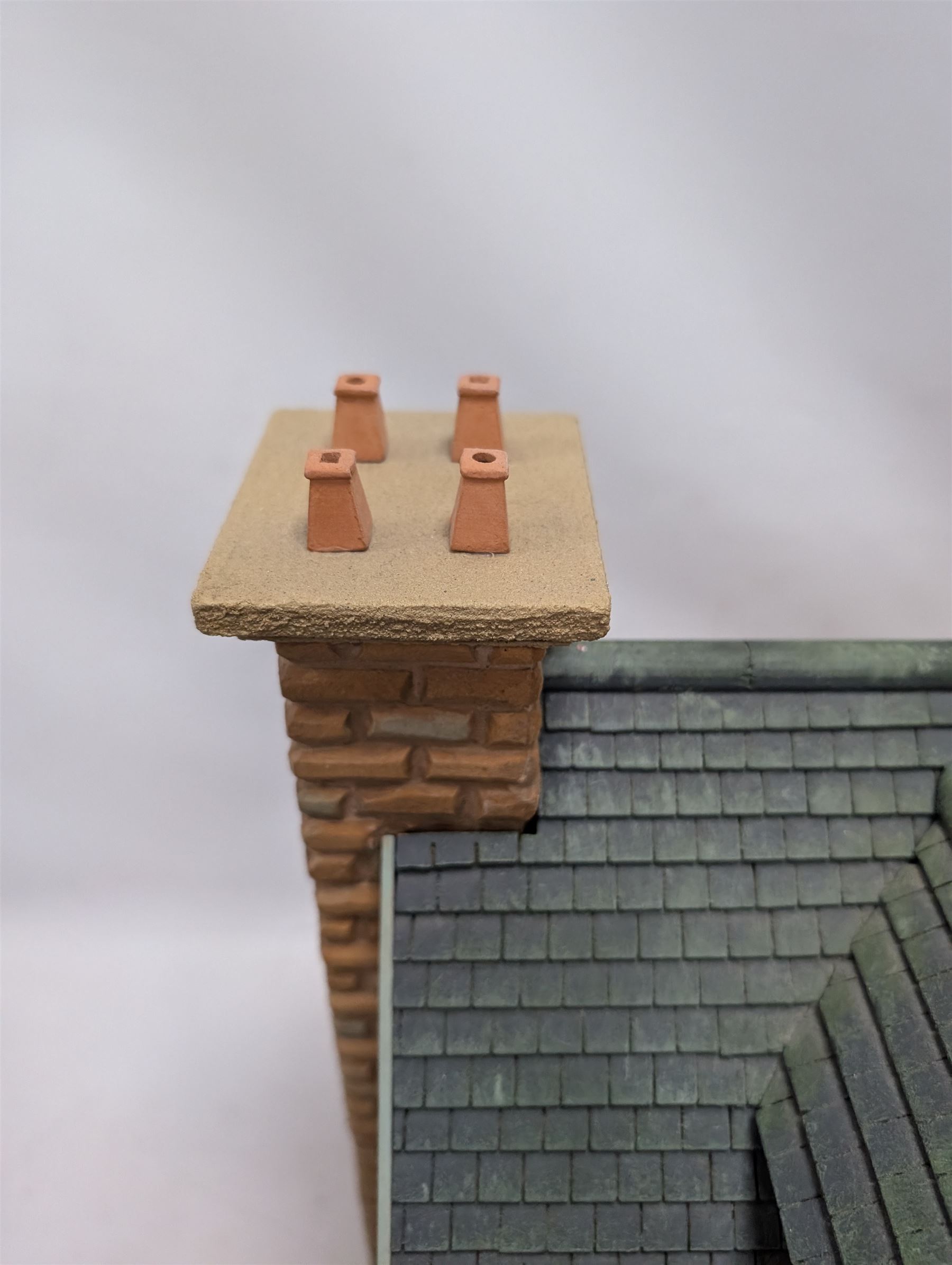 1:24 scale stone effect three-storey cottage dolls house, with green arched door and lattice effect windows, decorated to the interior with wooden floors, wired lighting and fire places, H45cm, W57cm, D26cm