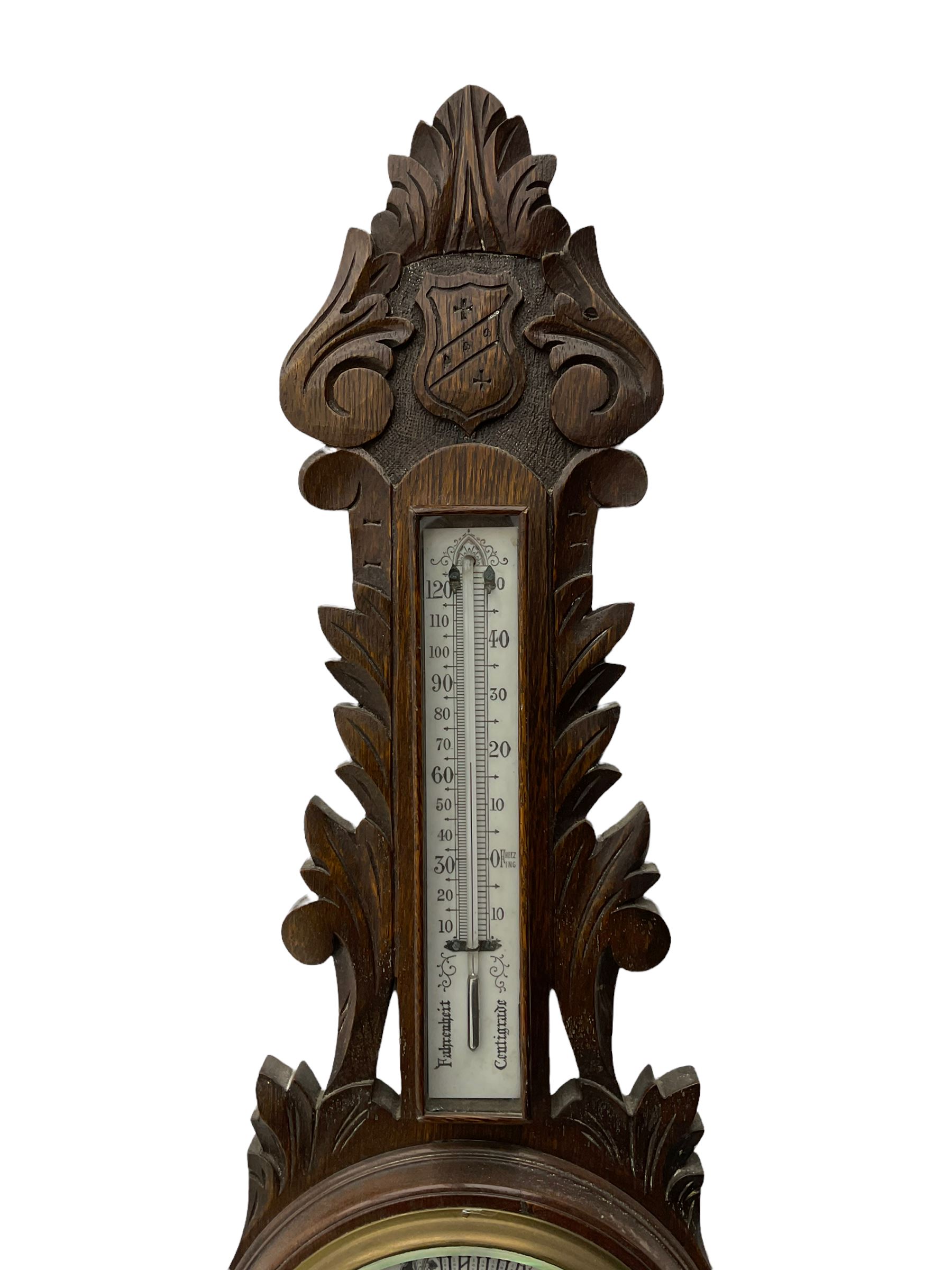 A 1920s oak cased patented aneroid barometer with openwork decorative carving, 8” enamel dial recording air pressure from 26 to 32 inches with weather predictions in gothic script, steel indicating hand and brass recording hand within a brass bezel and flat glass (glass cracked), with a boxed mercury thermometer recording the temperature in degrees centigrade and Fahrenheit.    

