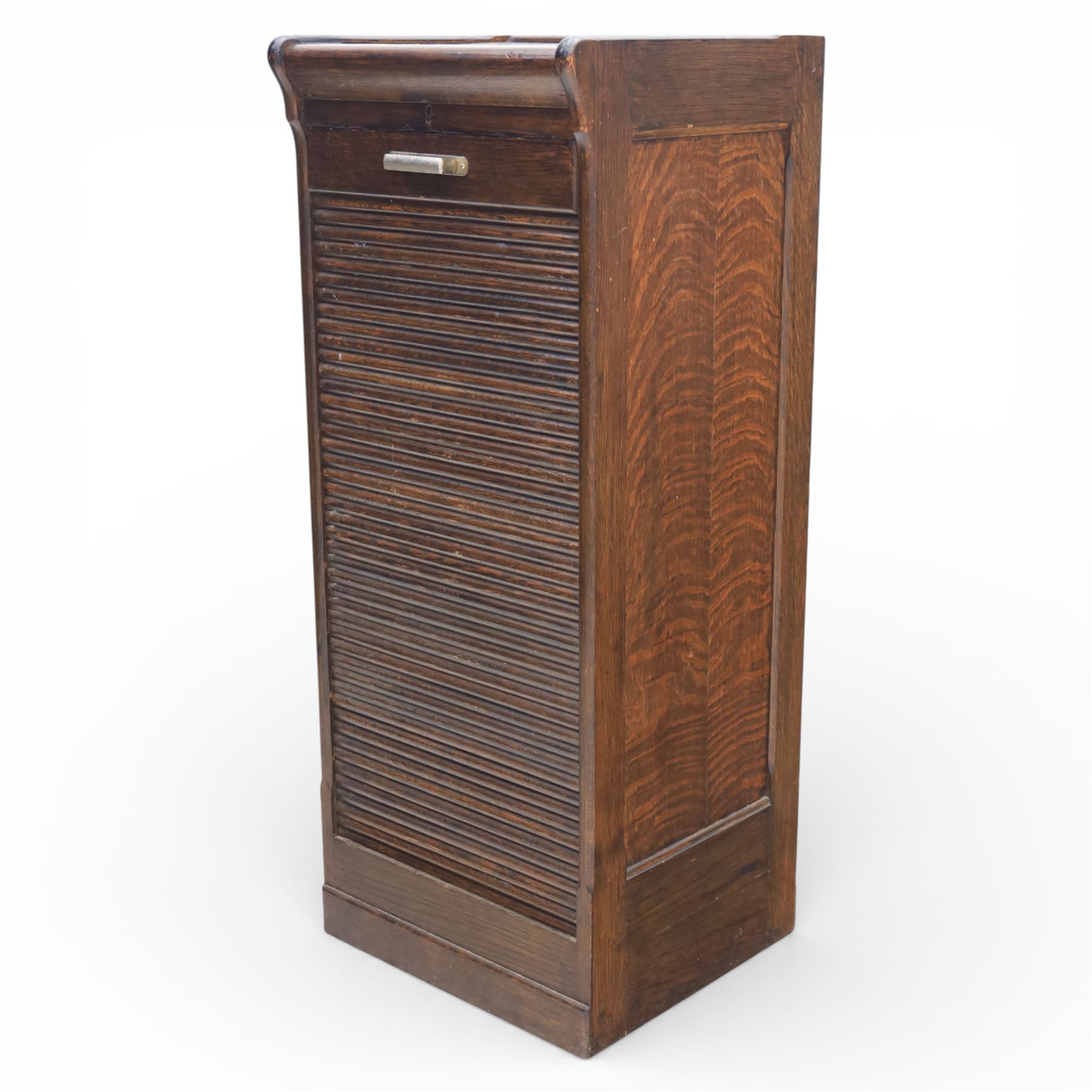 Early 20th century oak tambour front fitted cabinet, rectangular top with rounded corners over a roll tambour front enclosing a fitted interior of multiple shallow drawers with cut-out pulls, the sides with rounded uprights, on a stepped plinth base