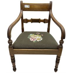 Regency mahogany elbow chair, carved shaped central back bar, over drop-in seat upholstered in floral needlework, raised on ring turned front supports