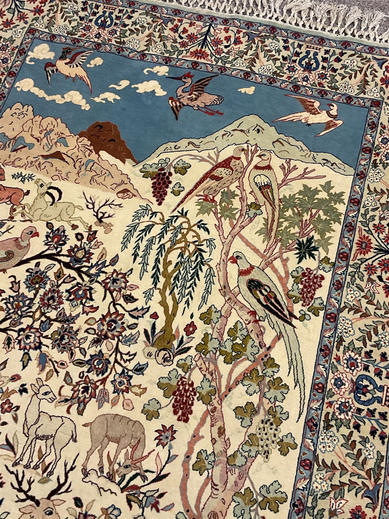 Fine Persian tree of life rug wall hanging, ivory ground field depicting landscape filled with animals, birds and flowers, the guarded border with stylised flower heads and foliage decoration, with brass hanging rail