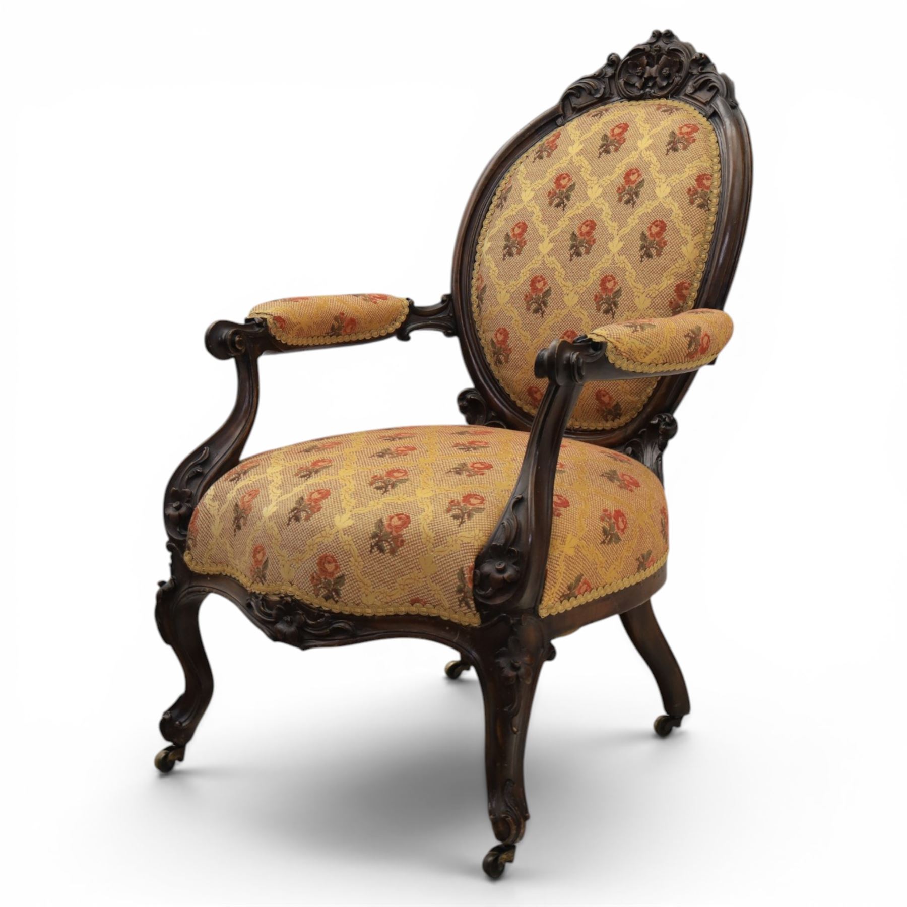 Victorian mahogany open armchair, oval stuff-over back with floral upholstery, moulded and foliate carved frame with pierced crest, padded open arms with scroll terminals, serpentine seat rail on cabriole supports