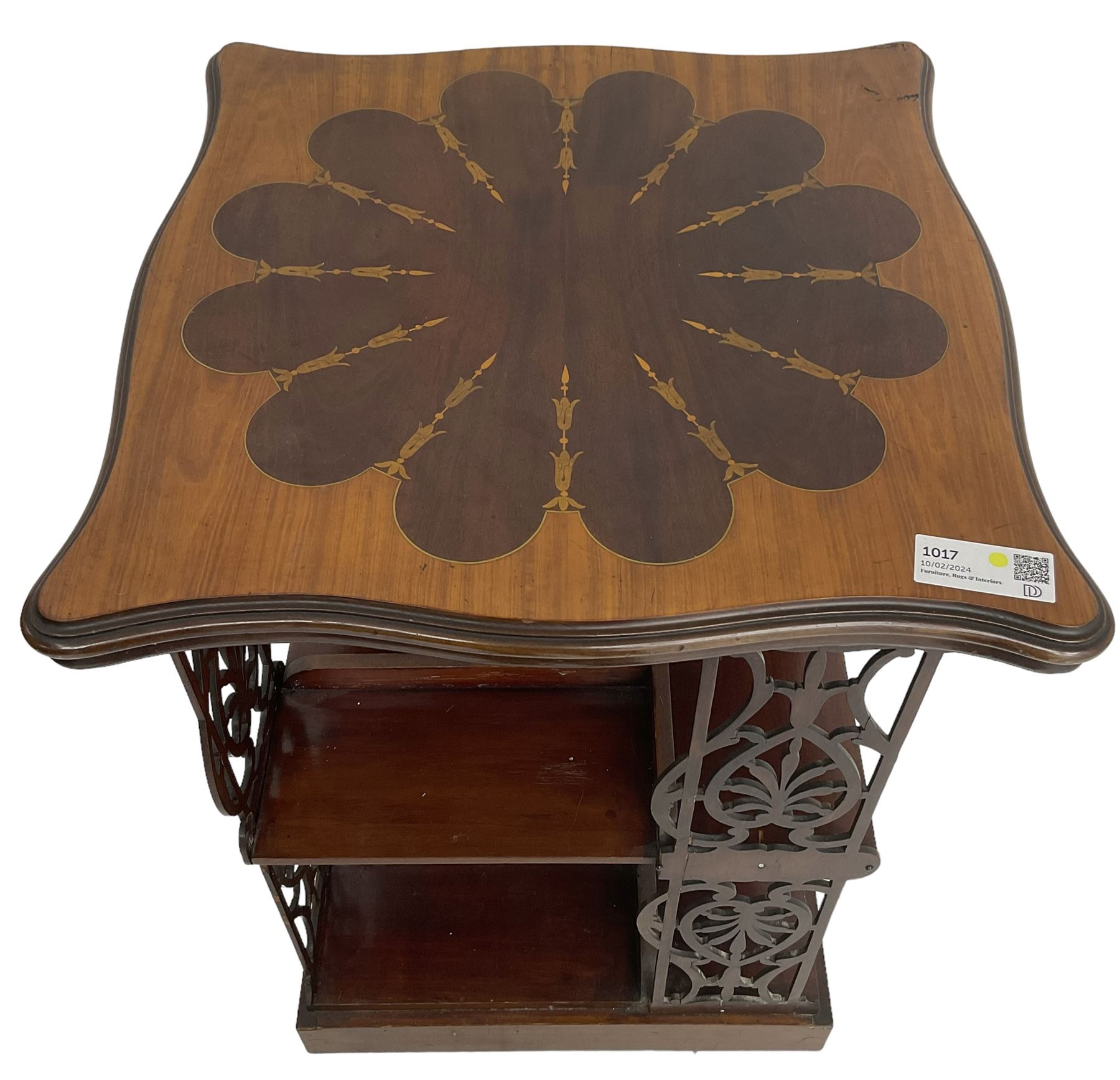 Edwardian mahogany revolving bookcase, the shaped moulded top inlaid with cusped panel and trailing bellflowers within a satinwood frame, foliate pierced upright splats and central square column supporting two tiers, on cruciform base with brass and ceramic castors 