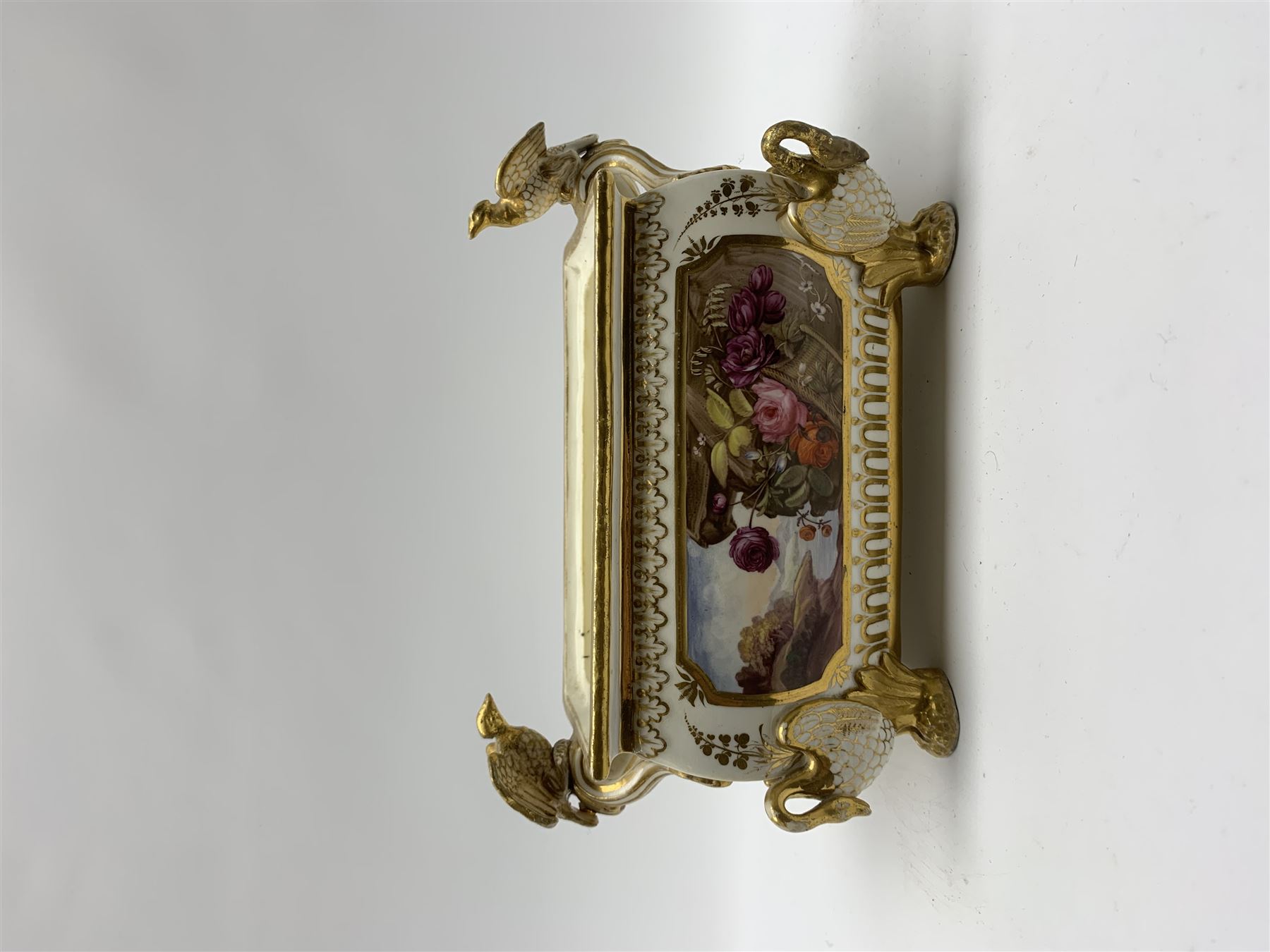 19th century Coalport bough pot, circa 1820, of bombe form, the body with twin handles surmounted by two birds and raised upon four feet modelled as swans, hand painted with two panels depicting an urn of flowers set against a mountainous landscape, the whole heightened in gilt throughout, H13cm L21cm