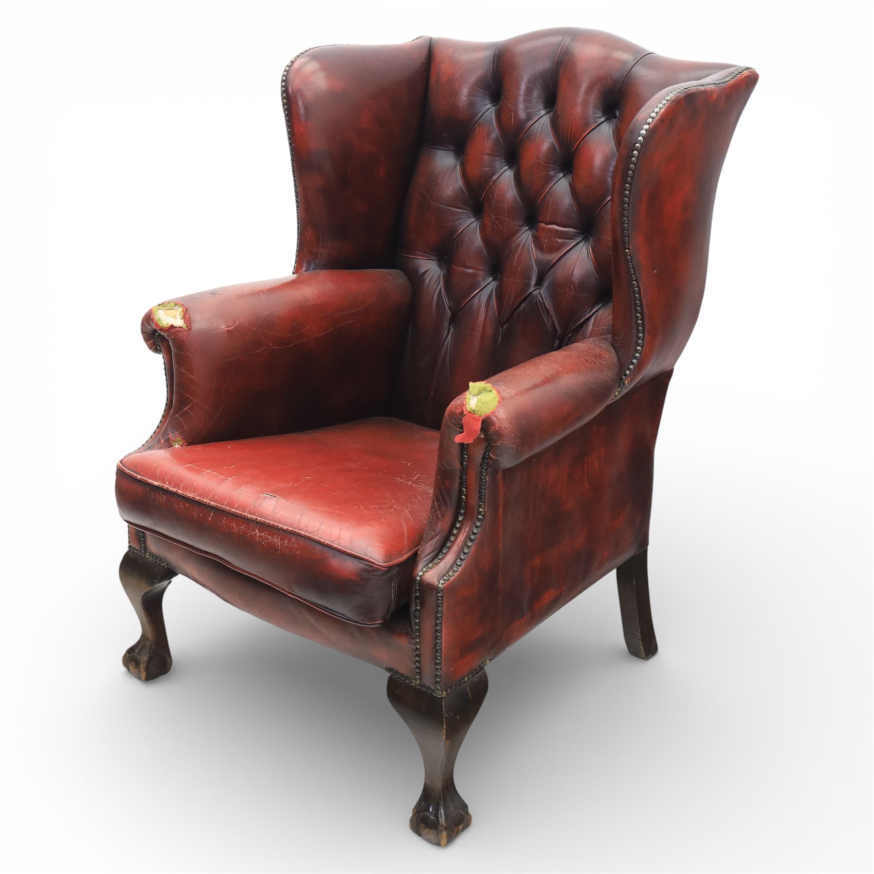 Georgian design wingback armchair upholstered in oxblood leather, the deep button upholstered back with shaped wings and out-scrolled arms, close nailhead trim to the edges, over a loose seat cushion, raised on cabriole front supports terminating in claw and ball feet