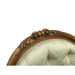 Victorian walnut framed nursing chair, the cresting rail decorated with carved applied flower heads and acanthus leaves, shaped back and sprung seat upholstered in buttoned ivory damask fabric, serpentine front over cartouche carved cabriole supports with ceramic castors (W57cm H92cm); with matched footstool, circular top over shaped moulded apron, on floral carved cabriole feet (W34cm) 