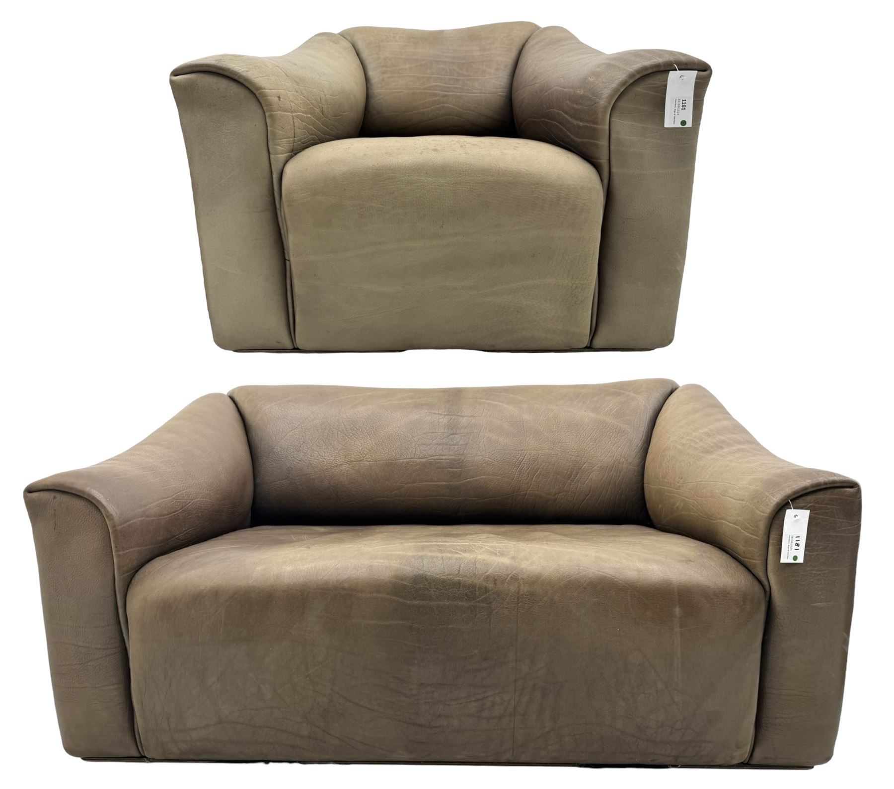 Mid-20th century two seater sofa, upholstered in soft brown leather with visible patina, curved arms and low back, on concealed supports (W138cm, D86cm, H72cm); matching armchair (W84cm, D86cm, H72cm)