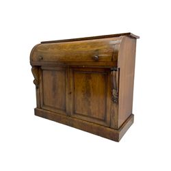 Victorian mahogany roll-top writing desk, top concealing fitted interior with pigeonholes and three drawers, the trisector inset writing surface with writing slope, base fitted with panelled cupboard enclosing single shelf, decorated with scrolled corbels