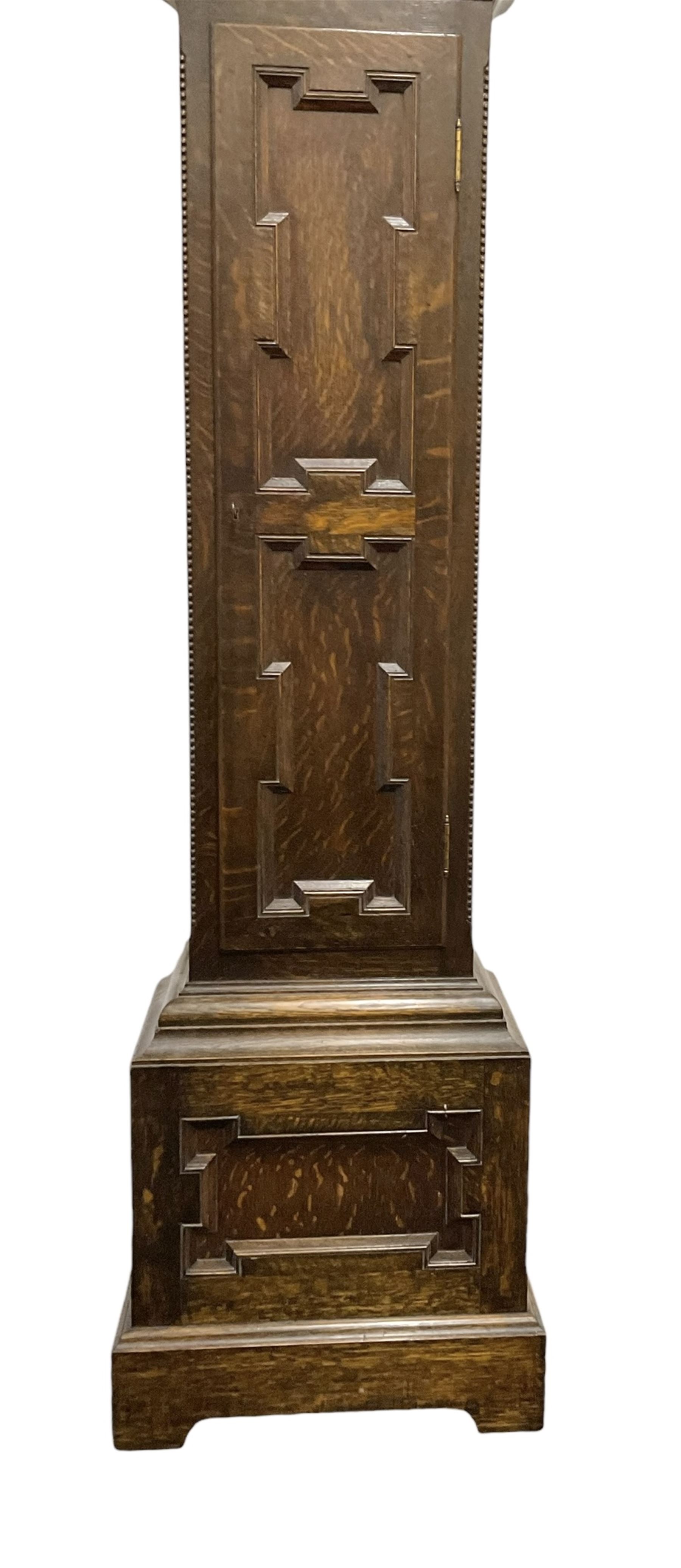 8-day oak longcase clock - in an early 18th century styled case with a caddy top, square hood door with barley twist columns, long carved trunk door on a conforming plinth with an applied skirting base, square brass dial with an engraved centre, silvered chapter and spandrels, 19th century rack striking movement, striking the hours on a bell. With weights and pendulum.
