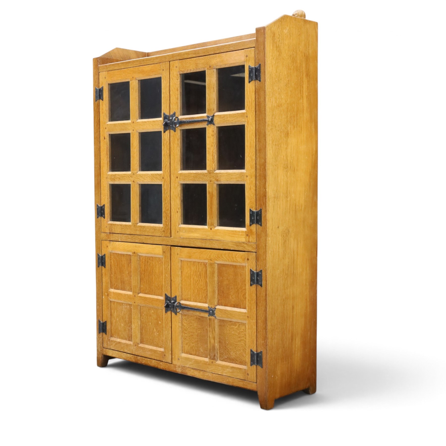Rabbitman - oak glazed bookcase or display cabinet, lightly adzed rectangular top with raised gallery, twin glazed doors enclosing two shelves, over a pair of panelled cabinet doors with wrought iron fittings, with carved rabbit signature, by Peter Heap of Wetwang