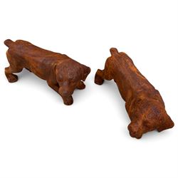 Pair of weathered cast iron garden ornaments modelled as playful Rottweiler puppies, in rusted finish