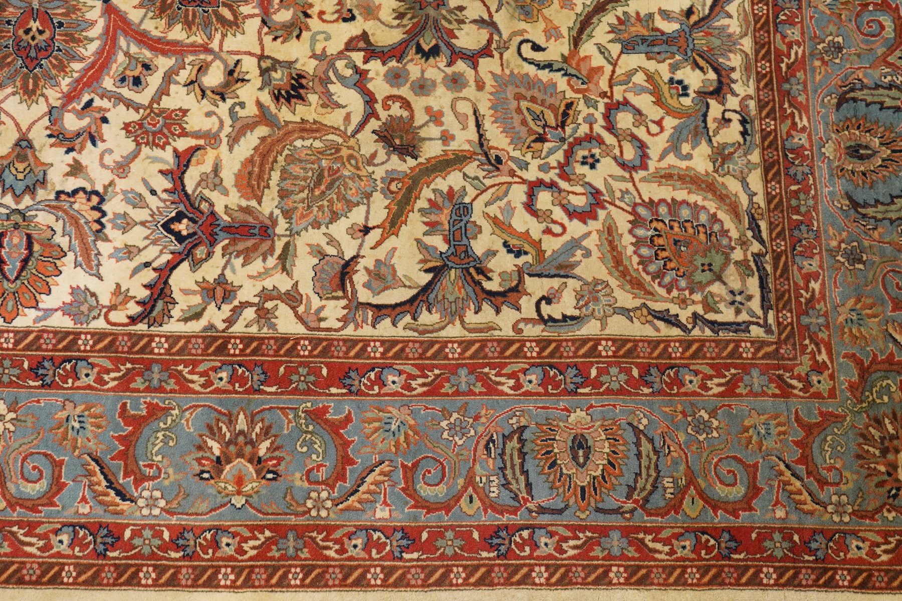 Persian Isfahan ivory and crimson ground rug, the busy field with central floral pole medallion surrounded by foliate motifs and stylised palmettes, the indigo guard line with repeating scrolling plant motifs