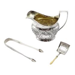 George III silver cream jug, embossed foliate decoration by Solomon Hougham, London 1805, silver caddy spoon with mother of pearl handle, makers mark I T, Birmingham 1807 and a pair of sugar tongs by Samuel Godbehere & Edward Wigan, London 1798, approx 5.1oz (3)