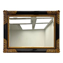 Early 20th century wall-hanging mirror, rectangular bevelled mirror plate within ebonised frame, gilt mounts to the corners carved with floral motifs 