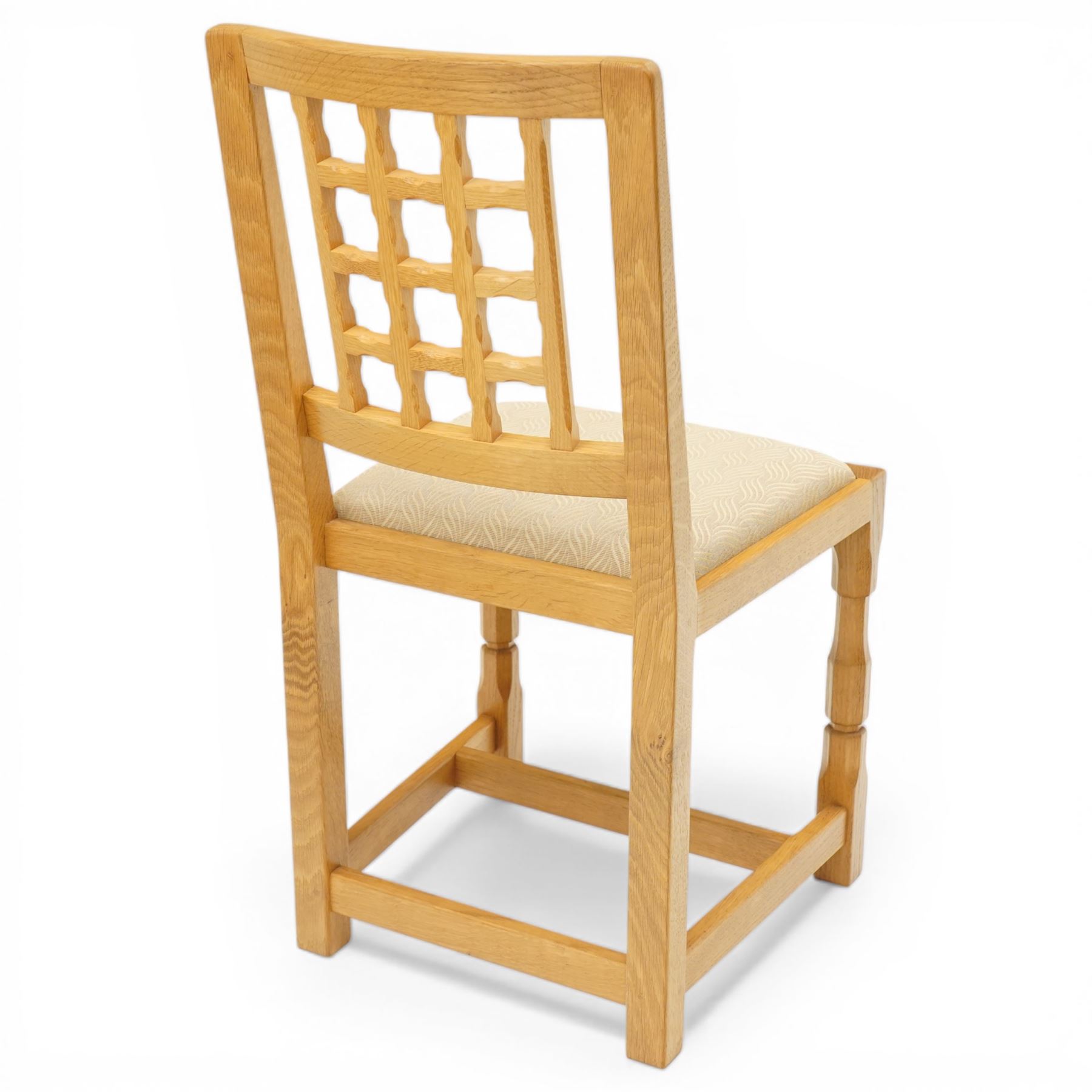 Knightman - eight oak dining chairs, the rectangular back with square section lattice splat enclosed by straight stiles and top rail, drop in upholstered seat in pale patterned fabric, raised on square section legs with chamfered detailing united by stretchers, with carved knight signature, by Horace Knight of Thirsk