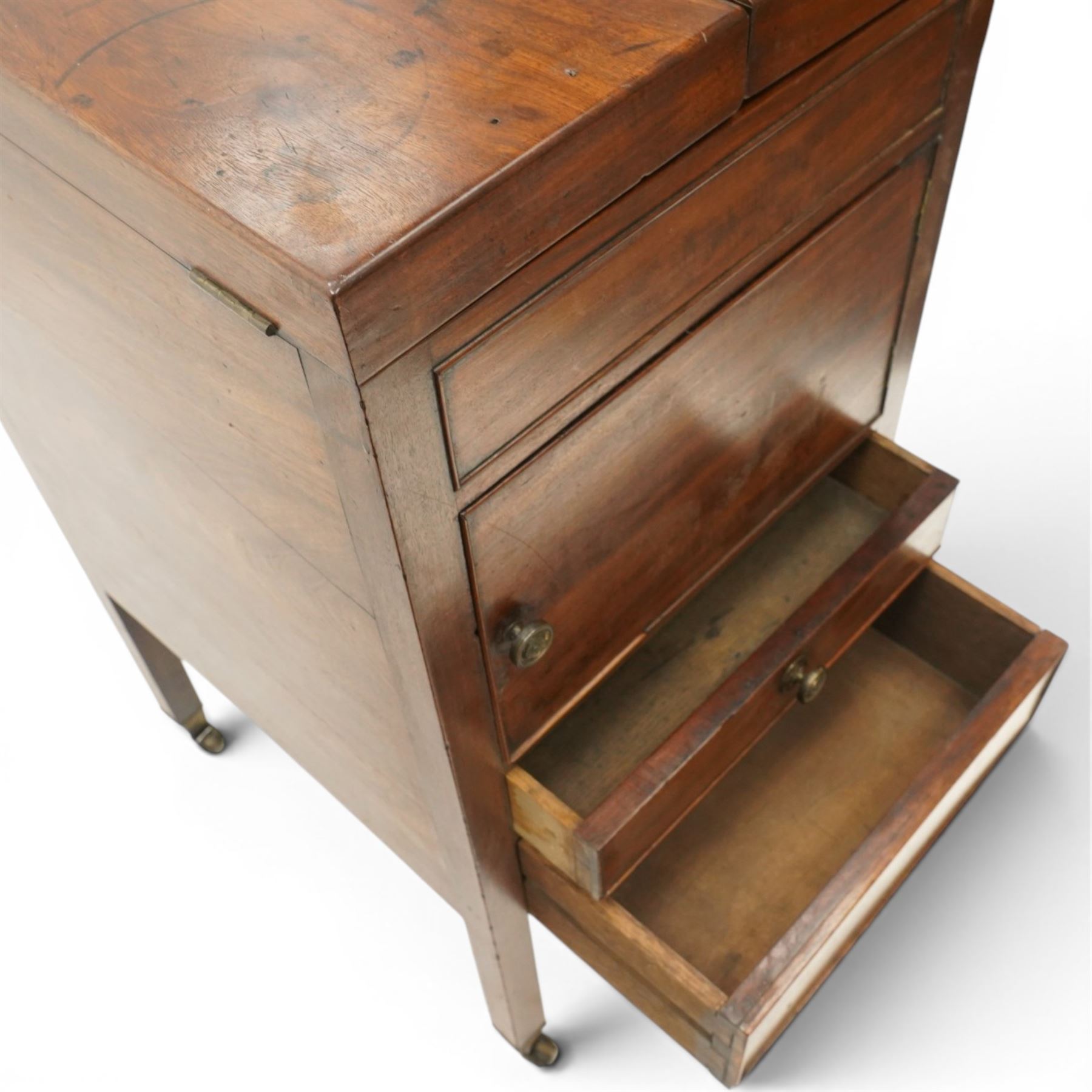 George III mahogany gentleman's washstand, rectangular double-hinged top enclosing fitted interior, over pot cupboard and two cock-beaded drawers, on square supports with castors