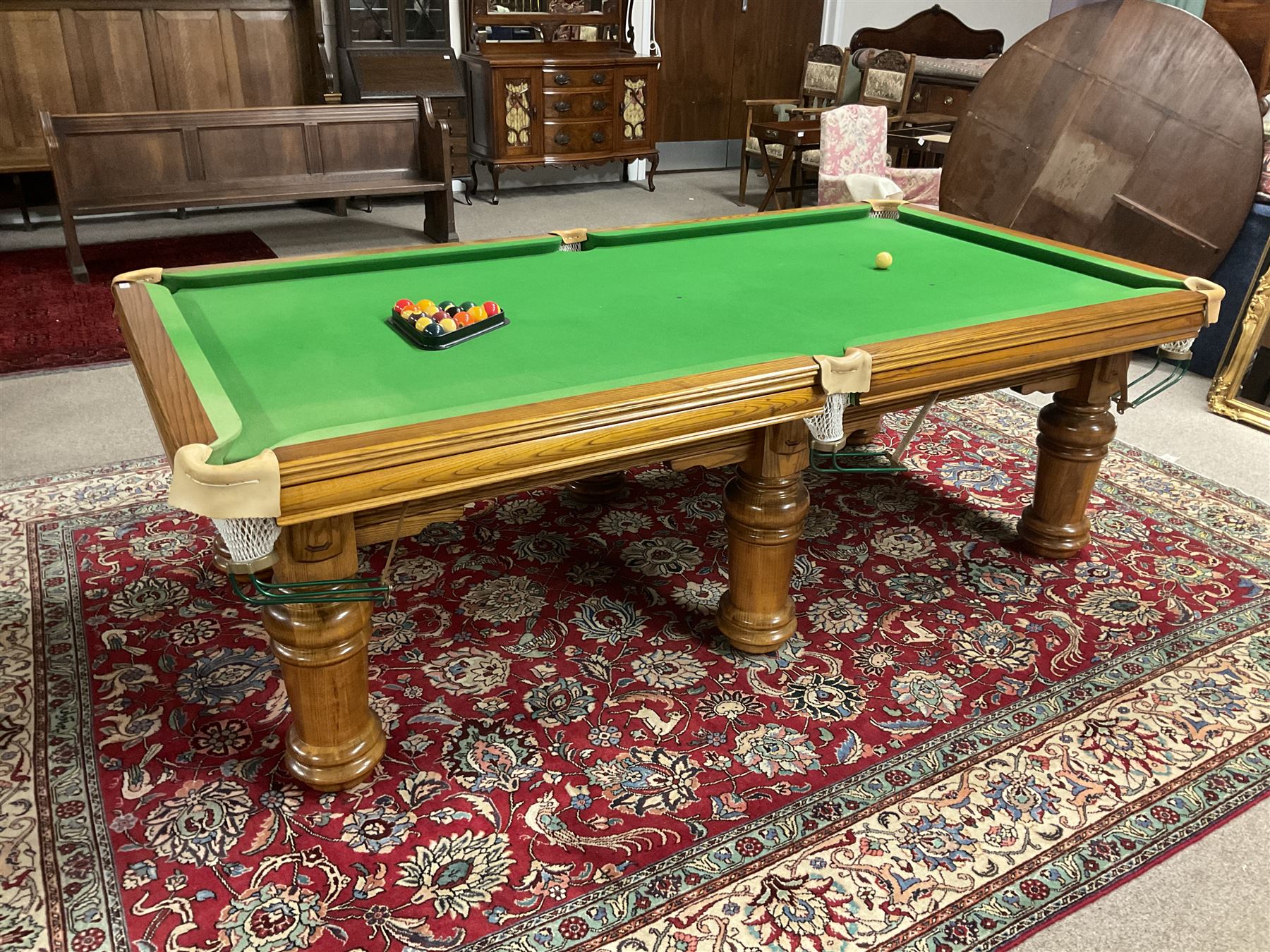 Late 20th century oak slate bed billiard table, on six turned column supports,  together with cues, ball set, baize brush, triangles and scoreboard 