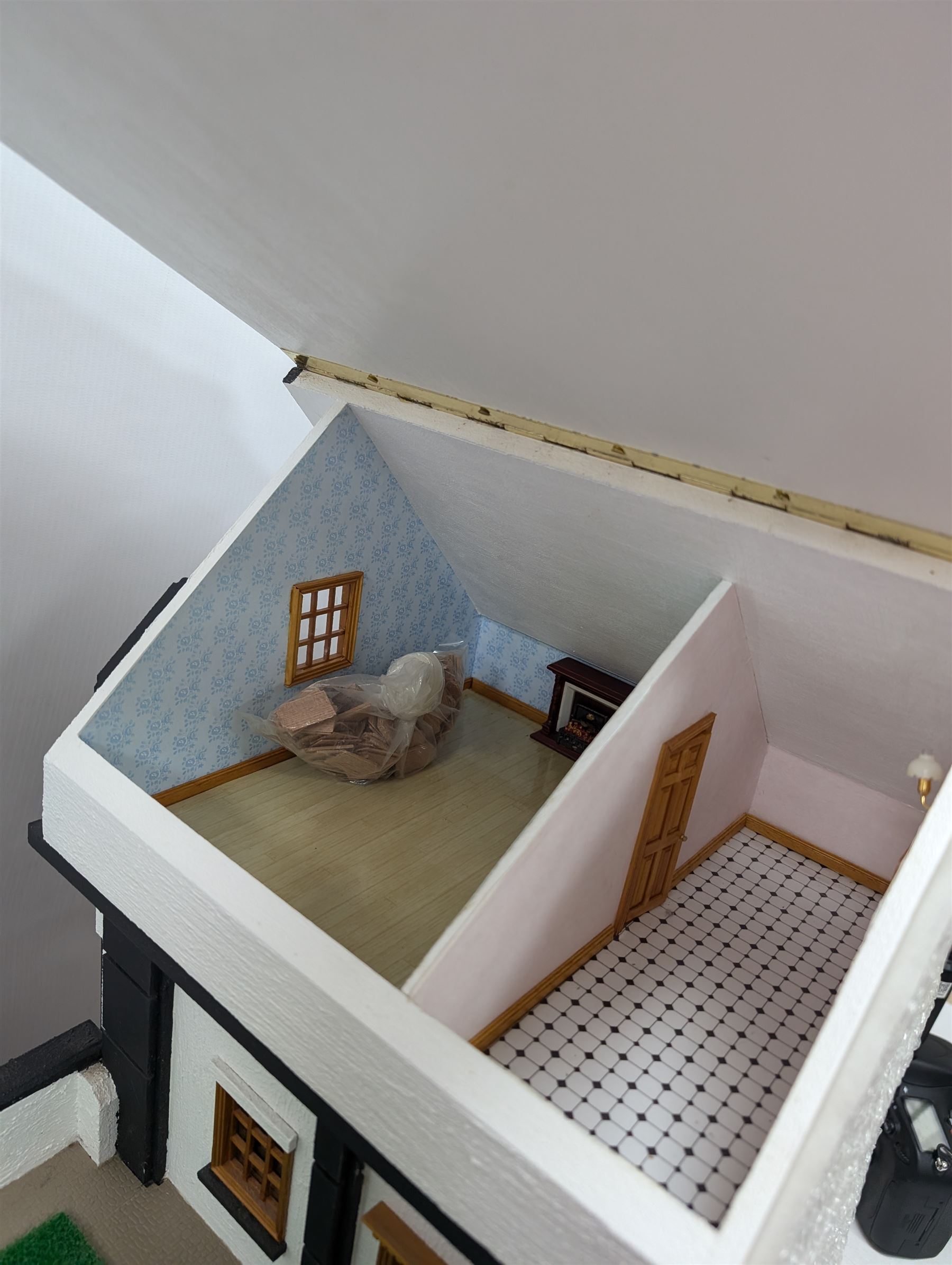 1:24 scale four-storey tudor-style dolls house, with black and white exterior, balcony garden, glazed panelled windows and wooden shingle roof, with decorated interior and wired fireplaces and lighting, H65cm, W58cm, D31cm, 