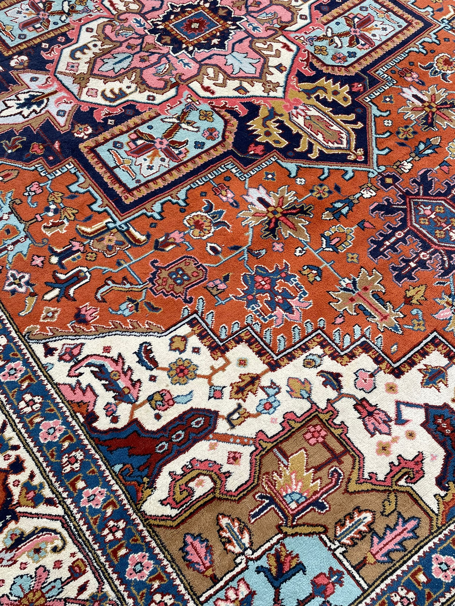 Large Persian carpet, the geometric and stylised floral medallion on rust ground field decorated with stylised plant motifs, guarded ivory border with repeating pattern