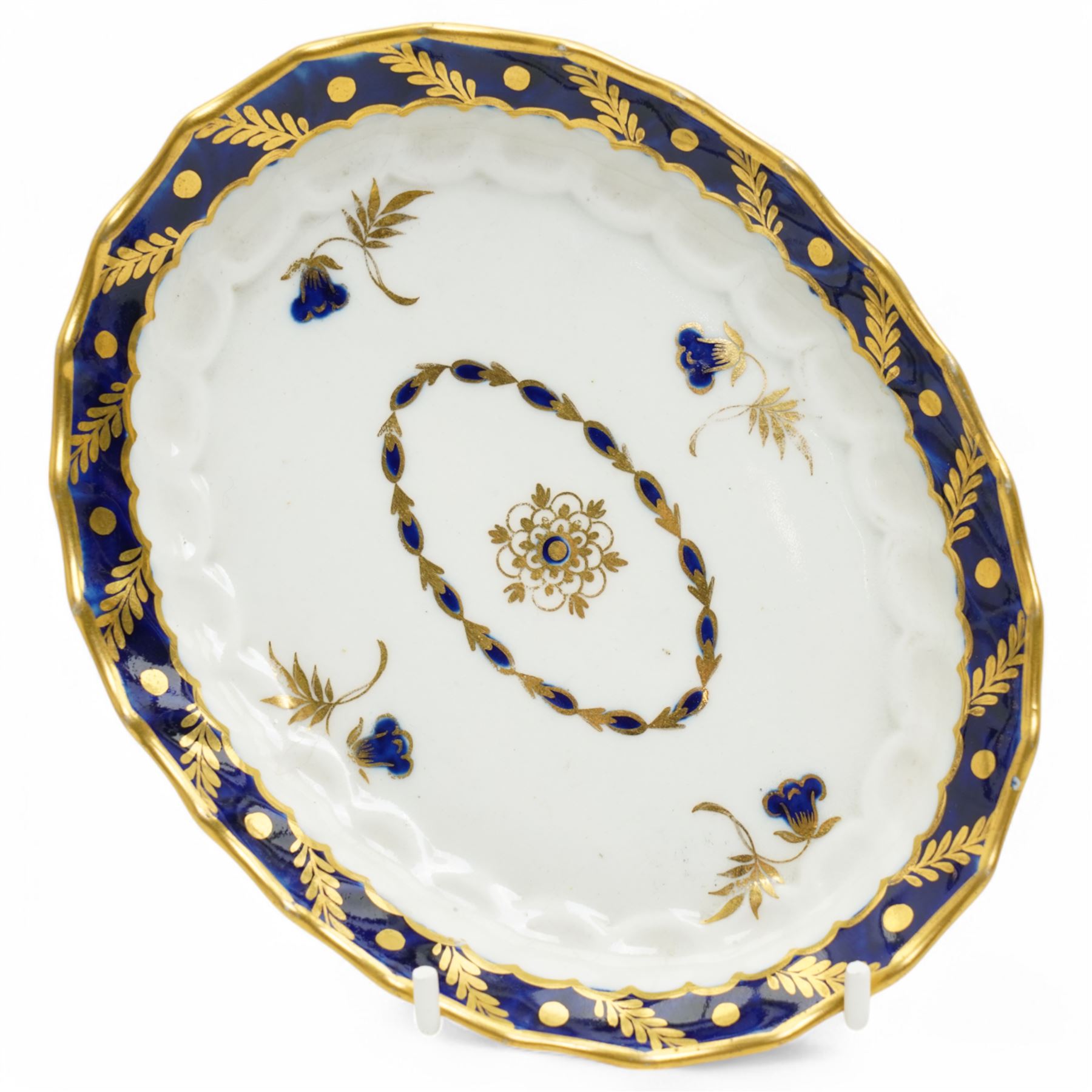 18th century Worcester teapot and stand of oval wrythen form decorated with flowers and leaves in blue and gilt, with blue crescent mark