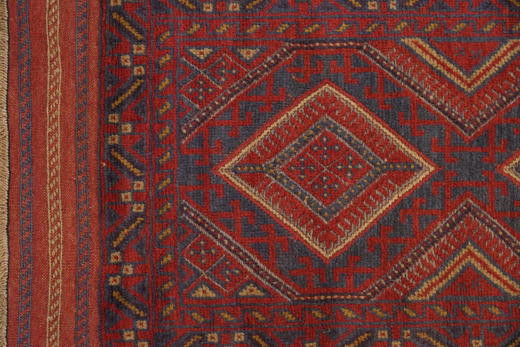 Near pair of Afghan Meshwani runner rugs, each with four red lozenge medallions on a blue ground interspersed with hooked geometric motifs, enclosed by patterned red borders, striped kilim end panels (2)