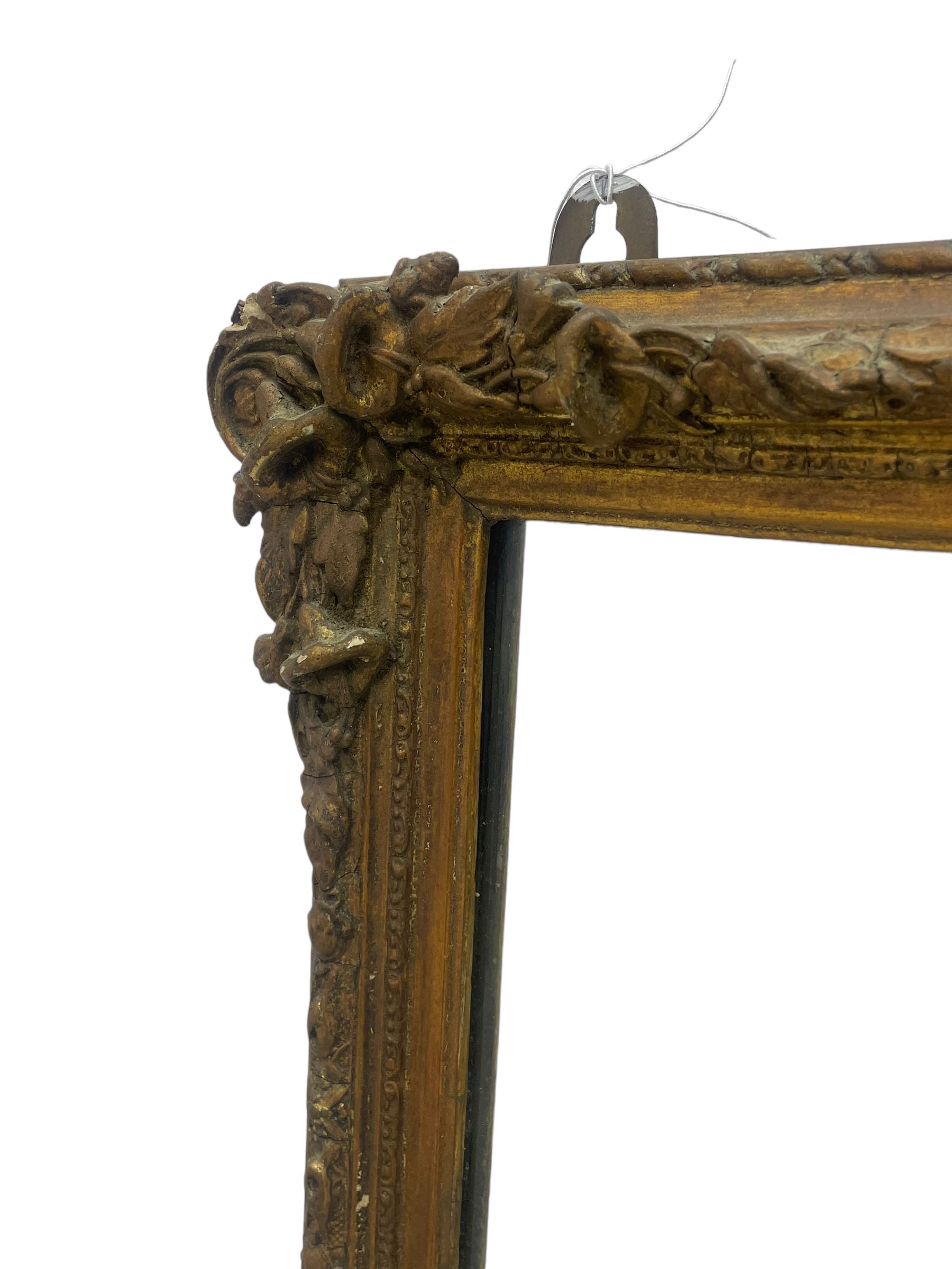19th century gilt framed wall mirror, the corners decorated with flower heads with extending foliage, plain mirror plate
