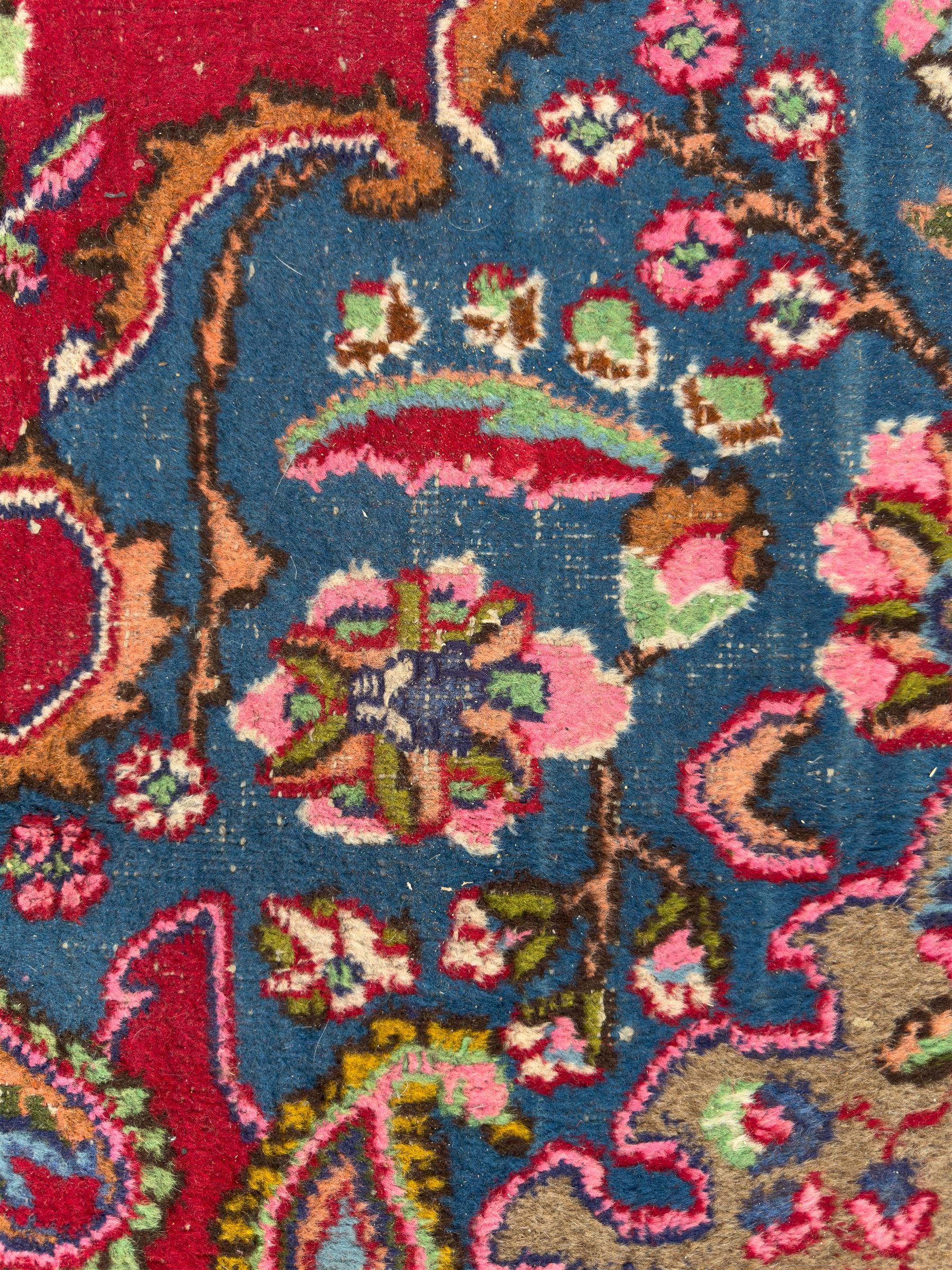Pair of Persian wool rugs, each with rich red ground, one centred with a diamond-shaped medallion and navy spandrels within a floral field, the other with radiating floral medallion and scrolling foliate motifs, both enclosed by multiple borders with palmette and flowerhead designs, from the region of Kashan 291x376, 299 x 378 