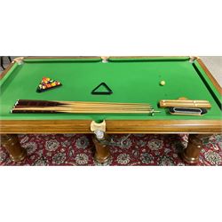 Late 20th century oak slate bed billiard table, on six turned column supports,  together with cues, ball set, baize brush, triangles and scoreboard 