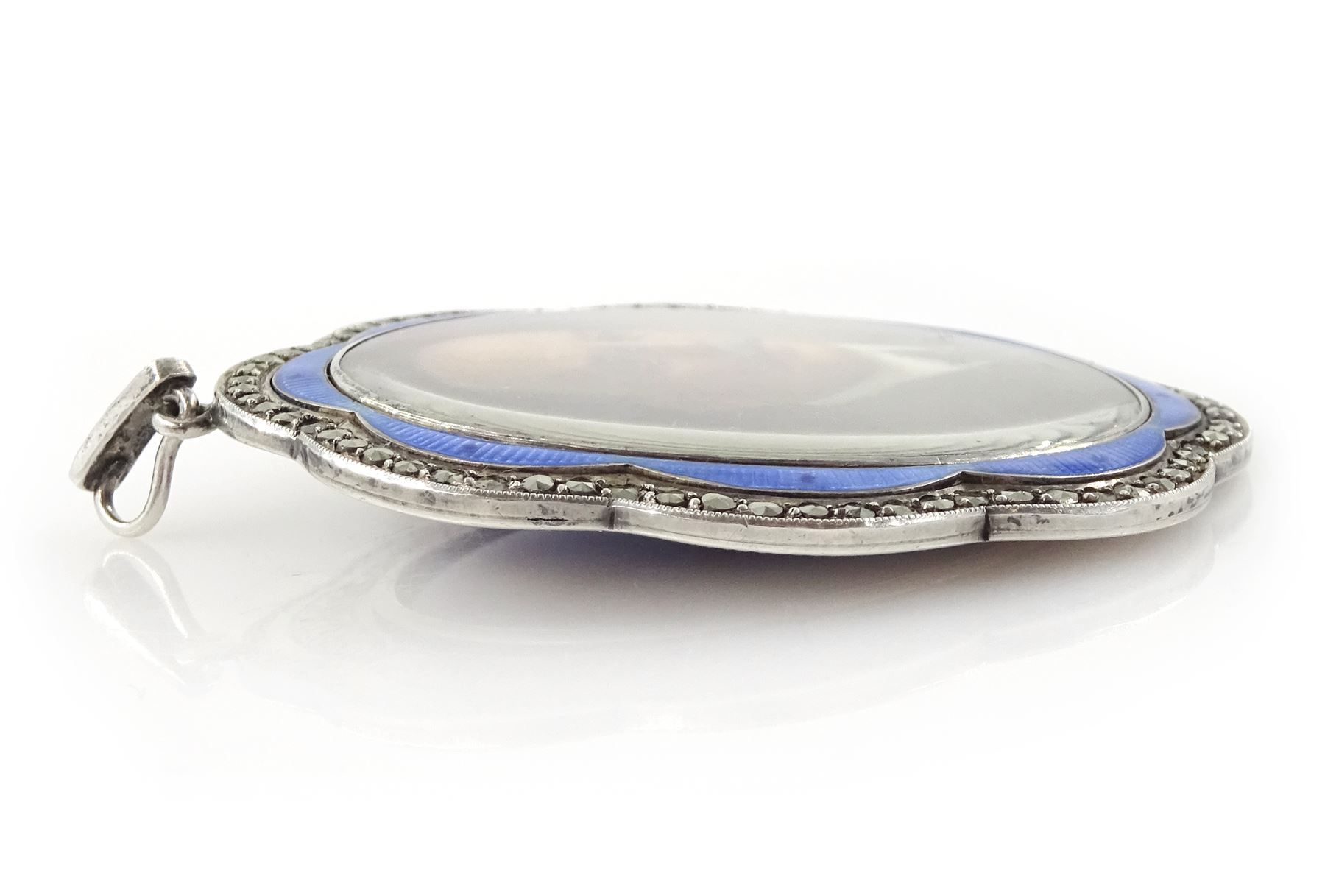 Early 20th century silver guilloche enamel portrait pendant, set with an oval miniature of a gentleman wearing a grey suit on ivory, within a blue enamel and marcasite border, the reverse set with a blue enamel panel and single split pearl, within a silver engraved border, suspended from a marcasite bail

This lot has been registered for sale under Section 10 of the APHA Ivory Act