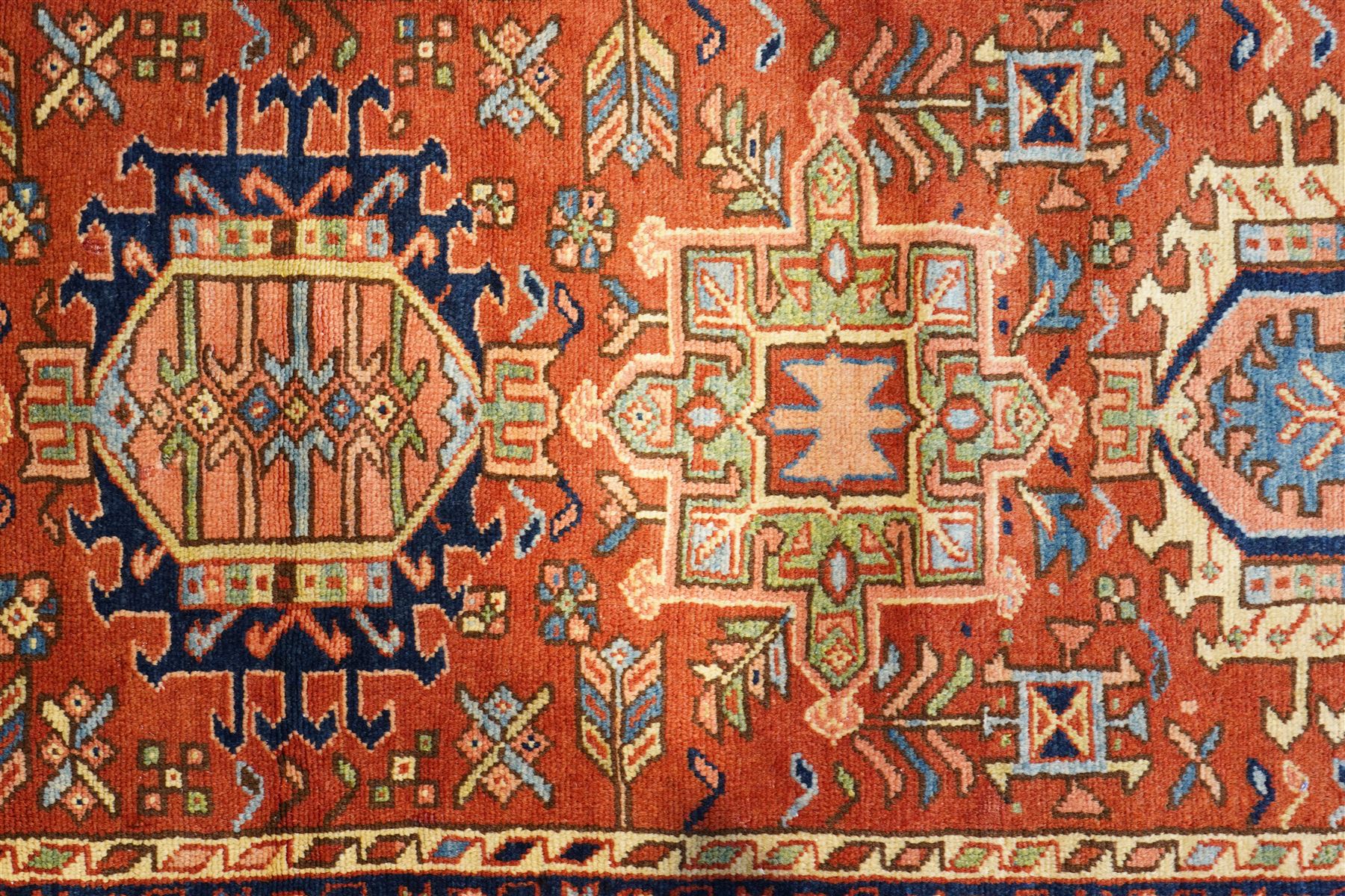 North West Persian Karajeh hand-knotted runner, field decorted with a series of linked stepped hexagonal medallions encloing stylized geometric motifs, surround by angular floral and tribal devices on a terracotta red ground enclosed a navy main border of repeating geometric and rosette motifs, between multiple guard stripes, with cotton fringe ends 