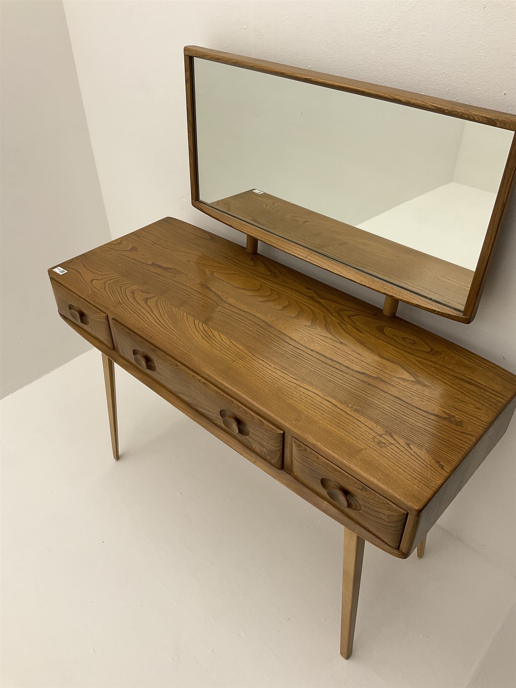 Ercol dressing table with raised back mirror, fitted with one long and two short drawers, raised on tapering supports 