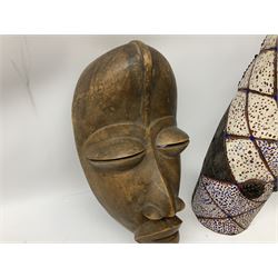 Two carved african spirit masks, together with a carved animal mask, painted and with beaded detail, largest example H86.5cm  