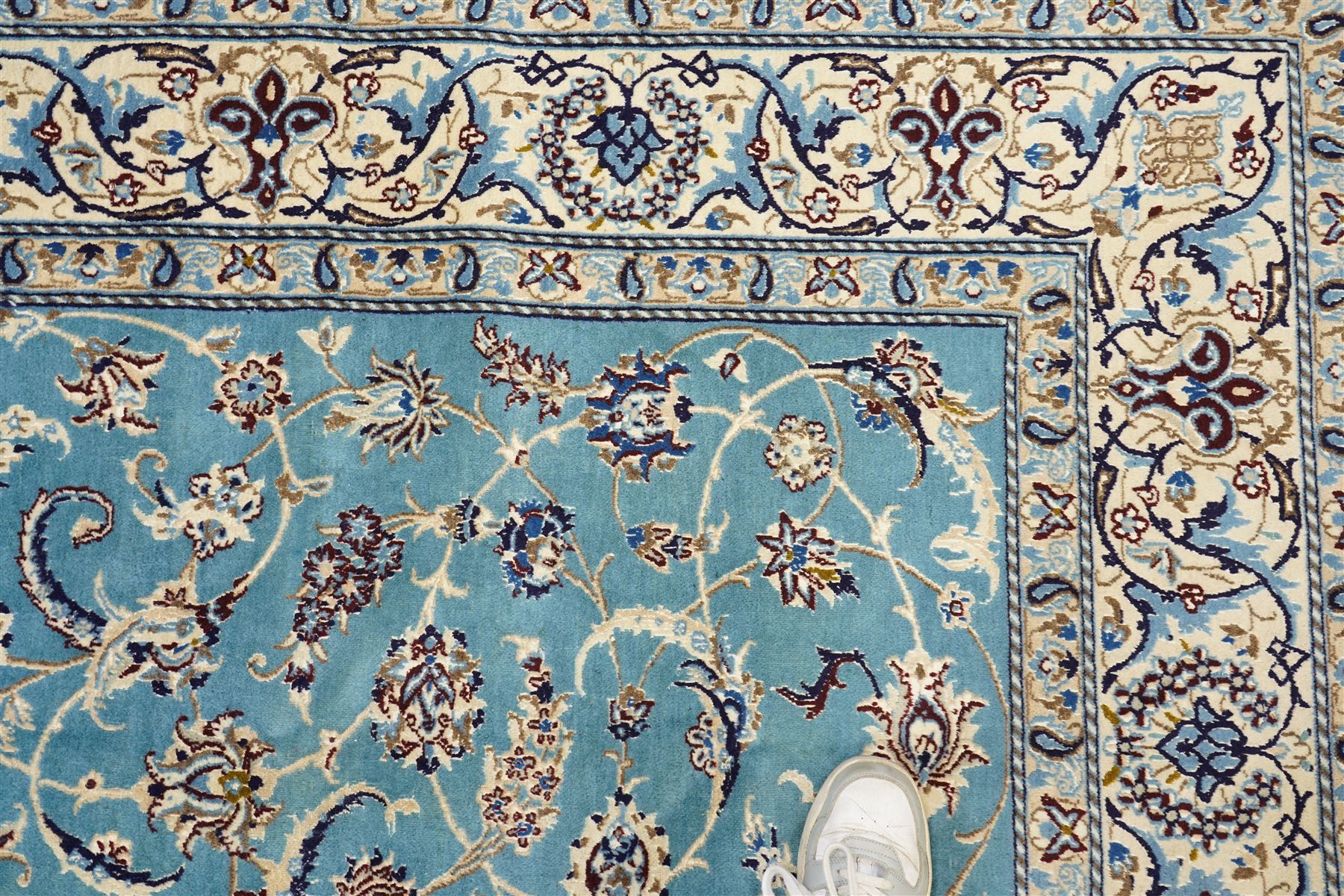 Central Persian Nain hand-knotted carpet, soft sky blue ground with central cusped medallion of radiating palmette form, issuing scrolling vine work, arabesques, and delicate floral sprays, spandrels of conforming design, main border of ivory ground decorated with scrolling vine work palmettes and stylized floral motifs, flanked by narrow guard stripes, with cotton fringe ends 