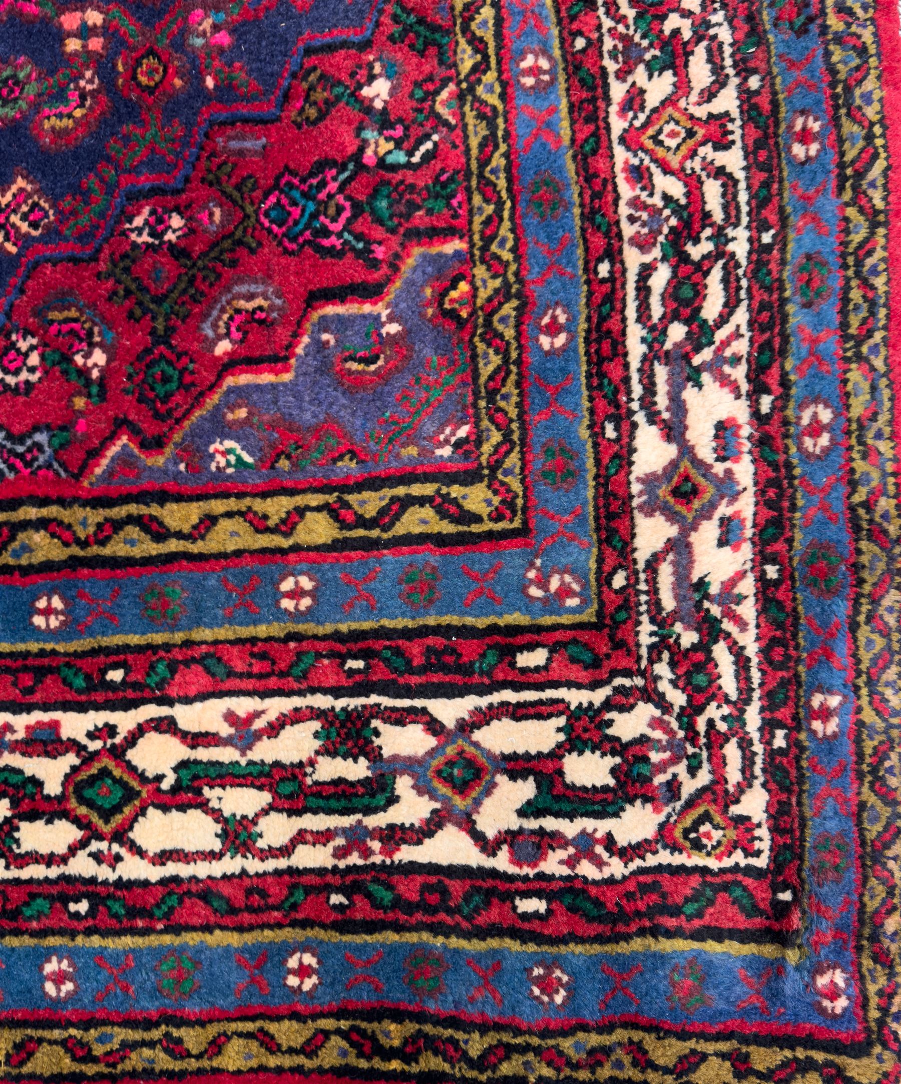 Northwestern Persian Hamadan hand-knotted rug, madder red field with a lozenge medallion enclosing an ivory centrepiece, indigo spandrels within an ivory border of stylized floral motifs between multiple guard borders 