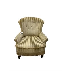 Late 19th century low seat armchair, upholstered in button back striped fabric with sprung seat, on front turned supports with castors