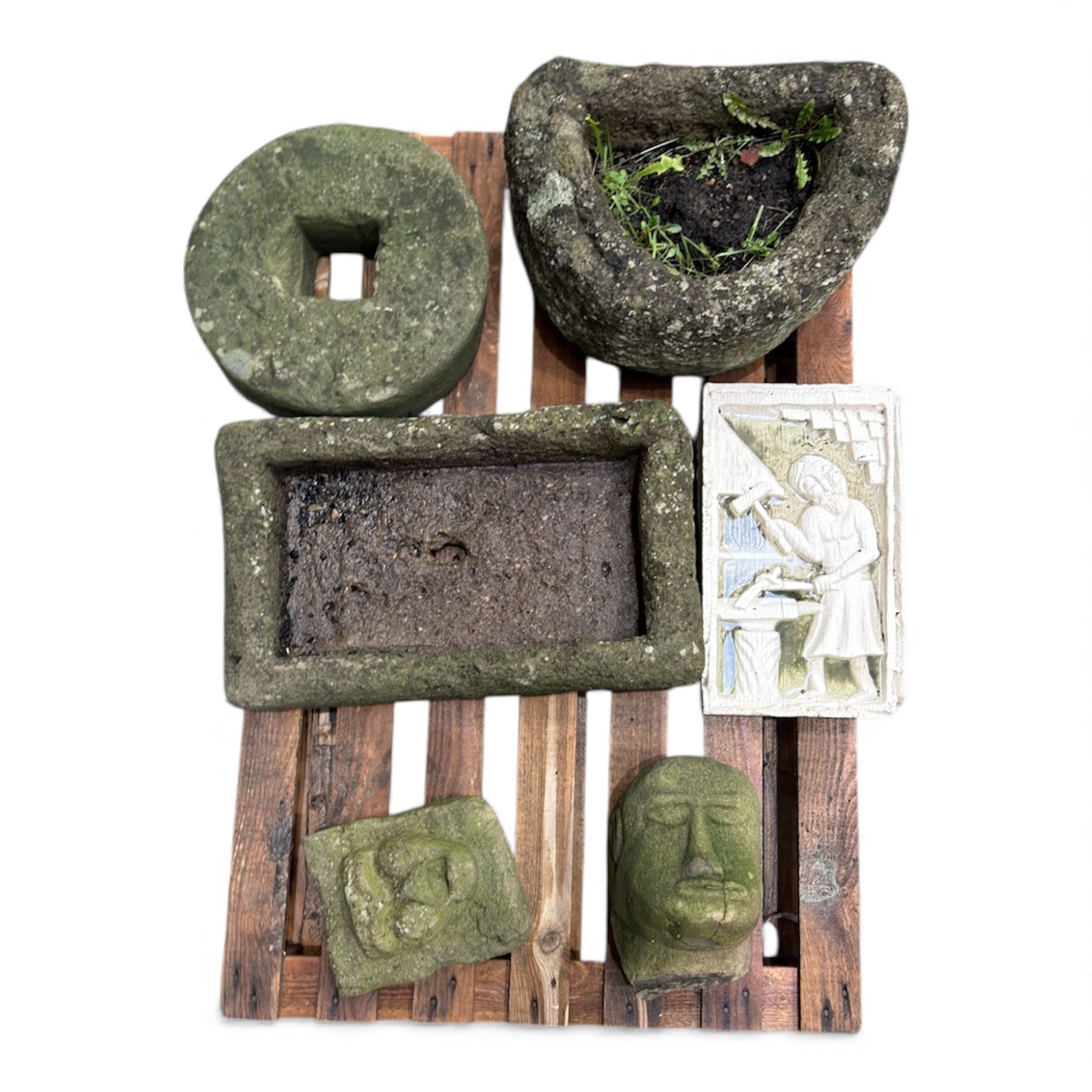 Collection of cast stone garden objects including mill stone, trough, planter, and faces