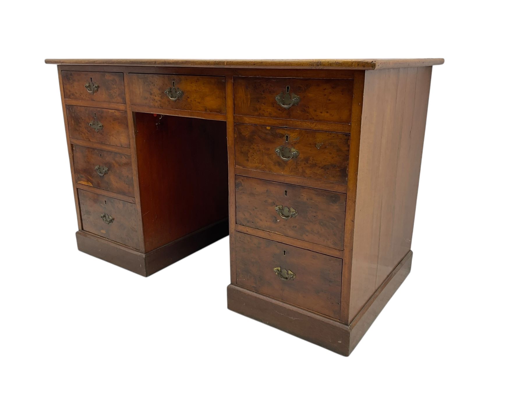 Late 19th to early 20th century walnut pedestal desk, rectangular top inset with red tooled leather writing surface, over a central frieze drawer flanked by two pedestals, each fitted with four graduated drawers with brass escutcheons and drop handles, the whole raised on a plinth base