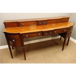  Regency mahogany sideboard, curved and canted break front top, raised back with cupboards enclosed by sliding doors, centre swag and ribbon mounts, two drawers and two cupboards, square tapering legs with peg feet, W224cm, H111cm, D79cm  