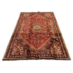 Persian Qashqai red ground rug, the main field decorated profusely with small stylised motifs, central lozenge medallion, multi-band border decorated with trailing foliate and flower head motifs 