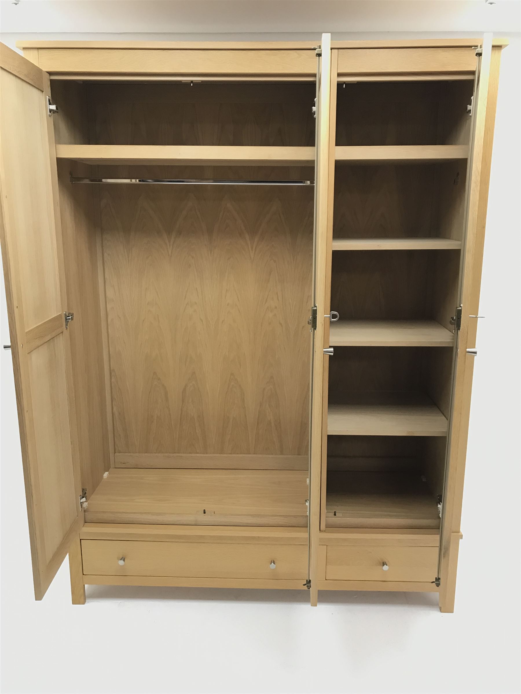Light oak triple wardrobe, projecting cornice, three doors enclosing fitted interior above one long and one short drawer, stile supports 