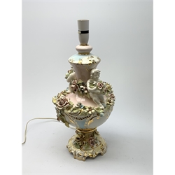 A Italian Capodimonte style lamp base, of pedestal urn form with applied putti and encrusted flower detail, heightened with gilt, overall H46cm. 