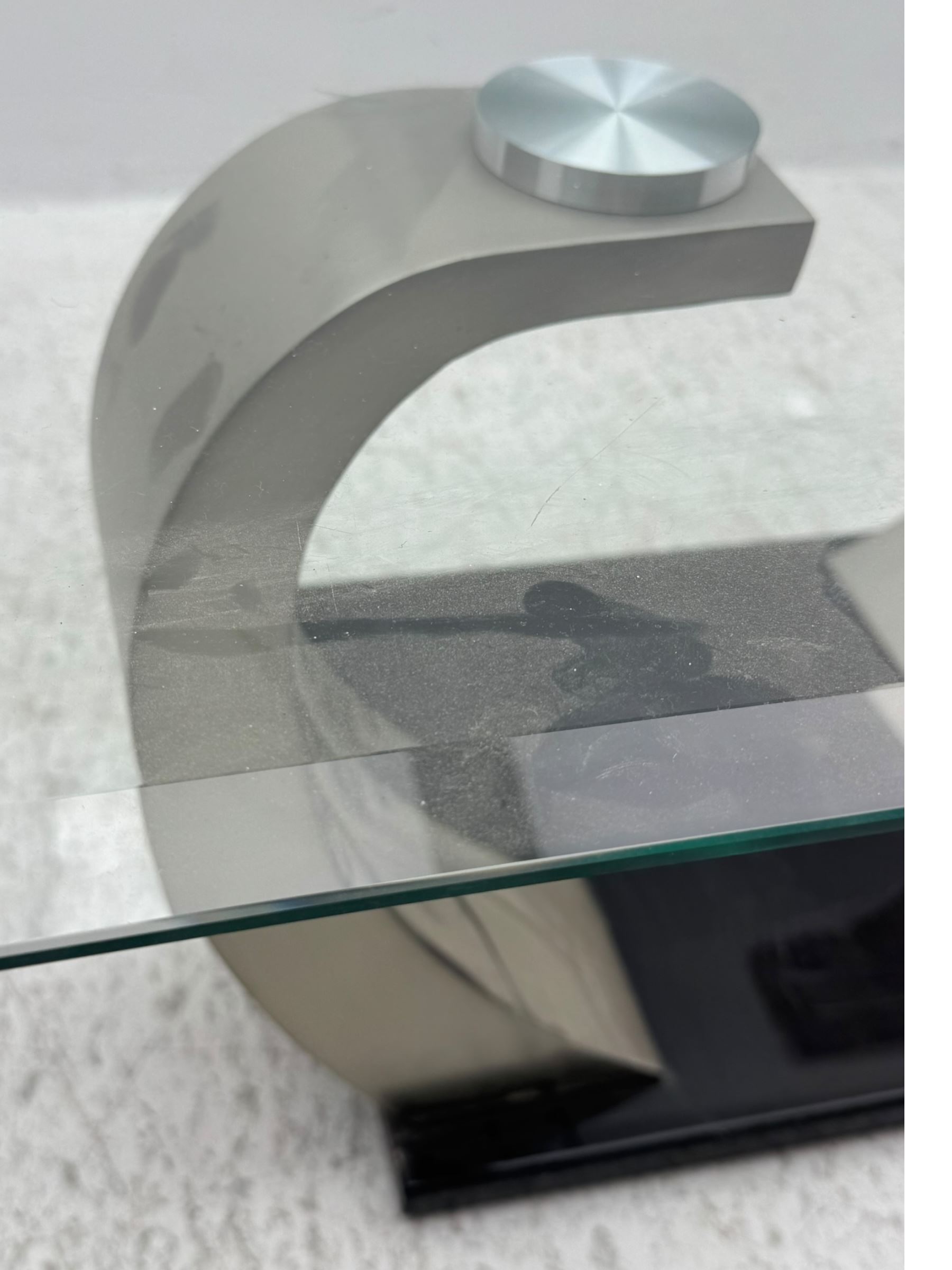Contemporary coffee table, rectangular clear glass top over brushed stainless steel curved supports, mounted on a rectangular base